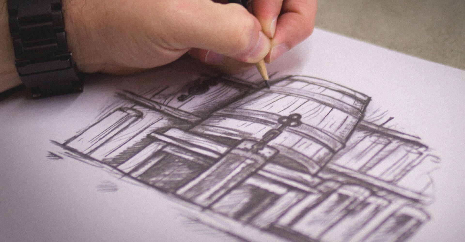 A person is drawing a building with a pencil on a piece of paper.