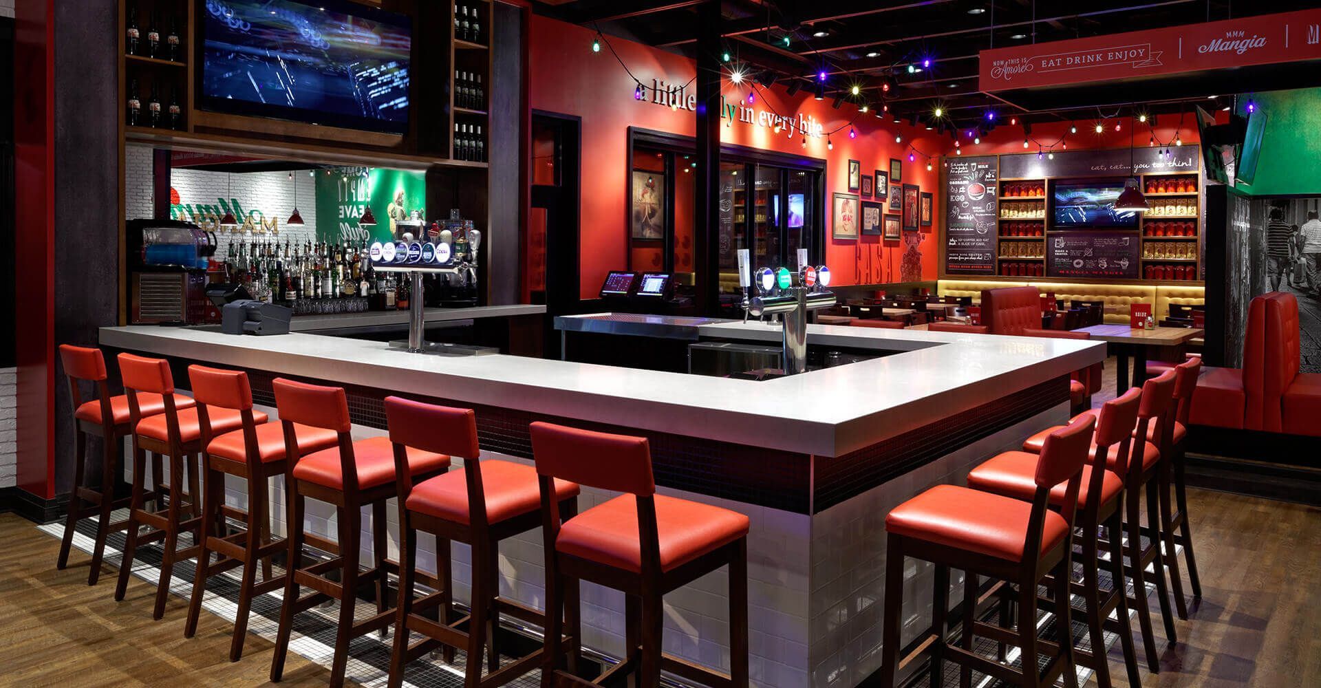 A restaurant with a long bar and red chairs