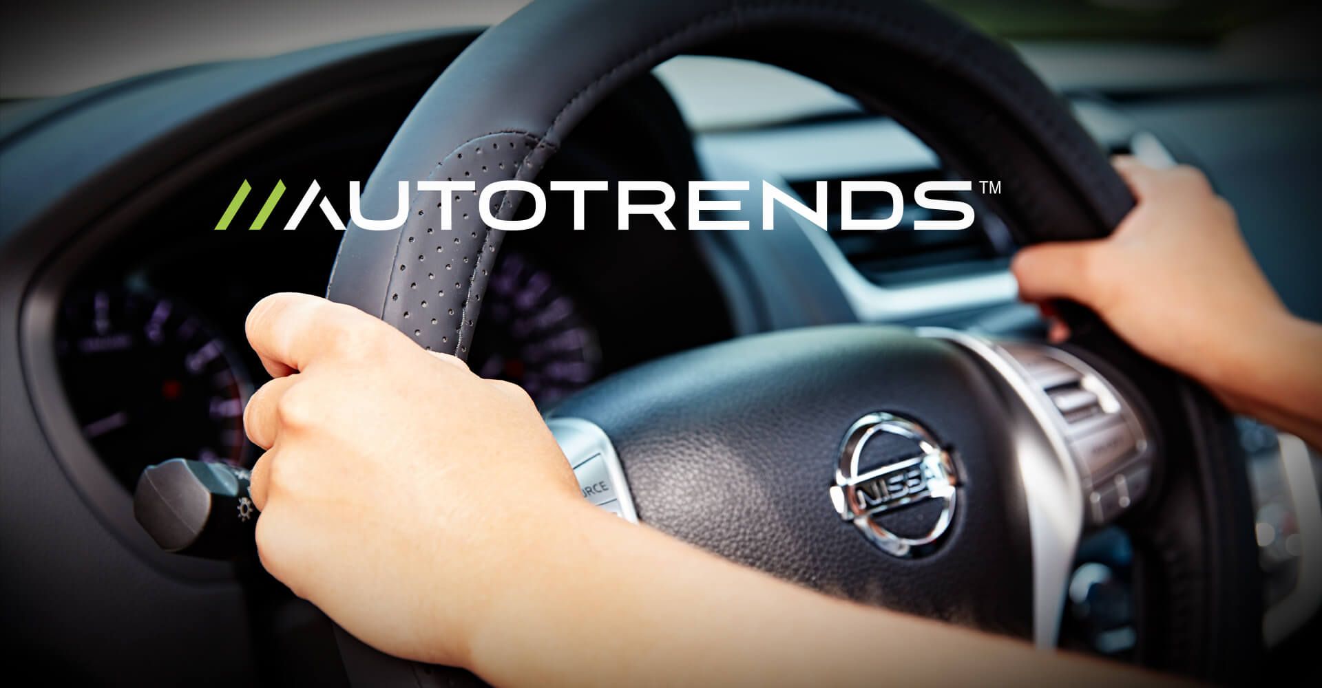 A person is holding the steering wheel of a nissan car