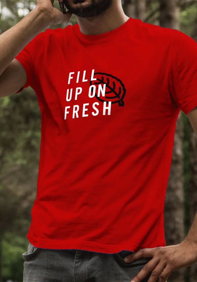 A man wearing a red t-shirt that says fill up on fresh