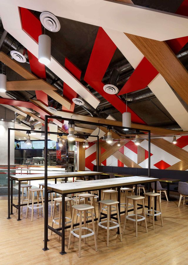 A restaurant with tables and stools and a red and white ceiling