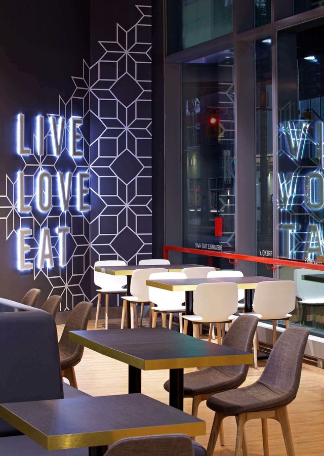 A restaurant with tables and chairs and a neon sign that says live love eat