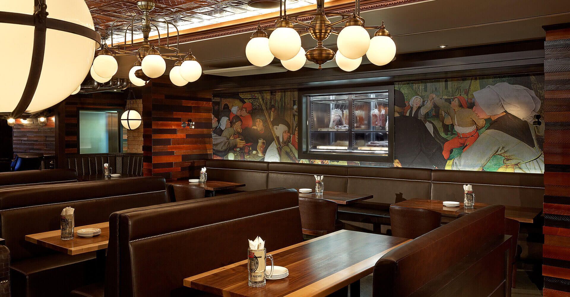 A restaurant with tables and benches and a mural on the wall.
