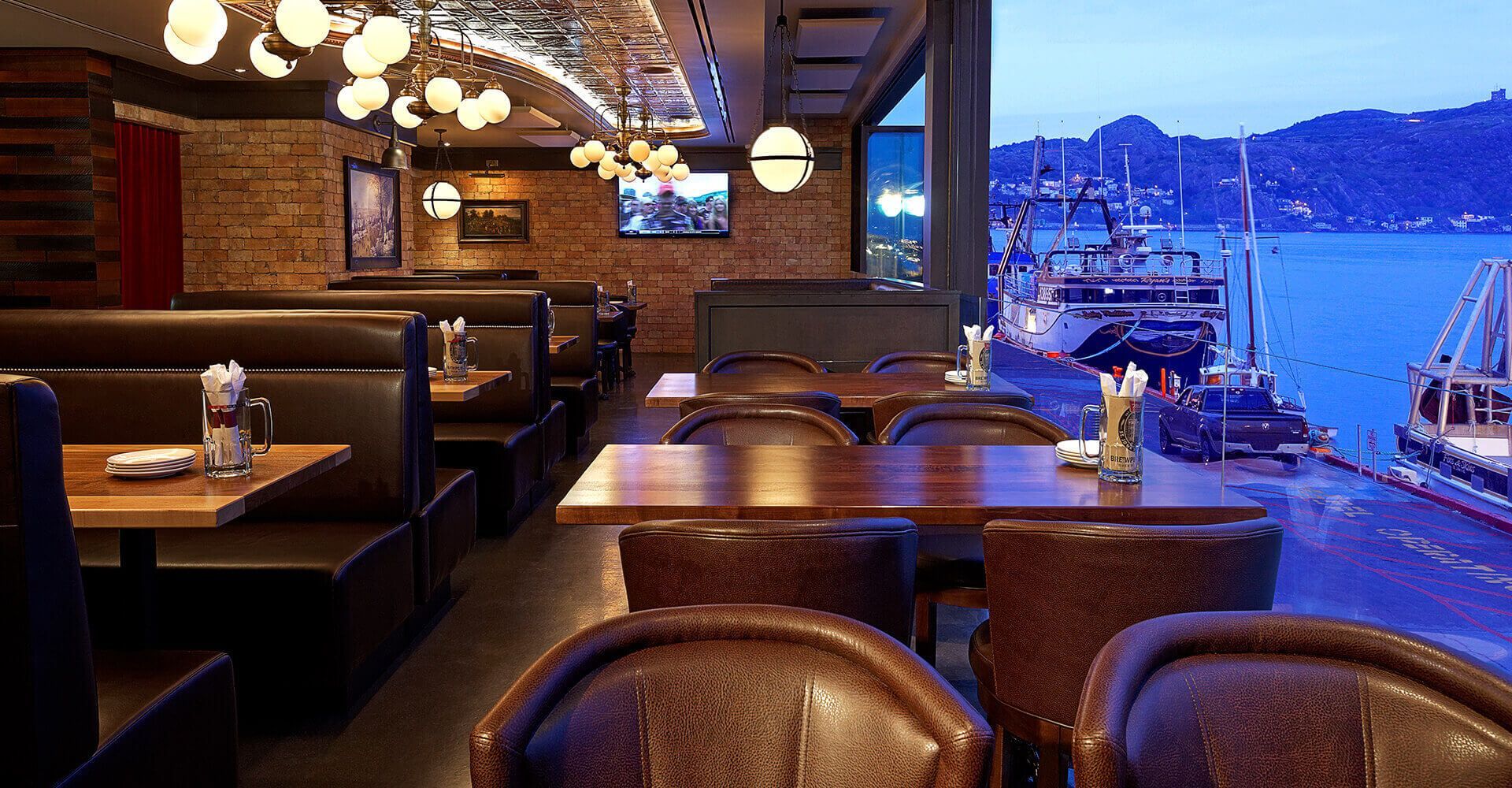 A restaurant with tables and chairs and a view of the water.