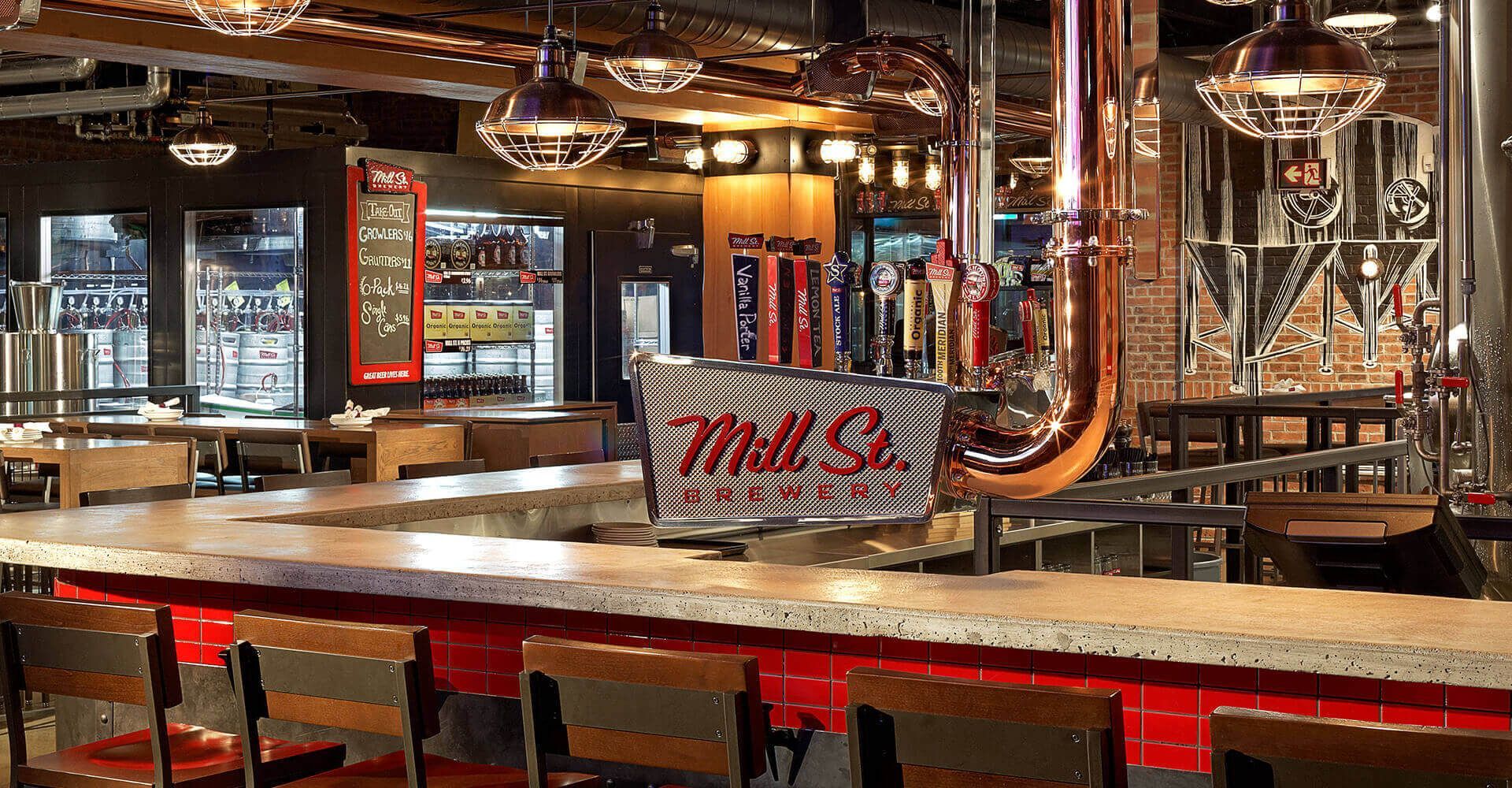 A restaurant with a long bar and tables and chairs.