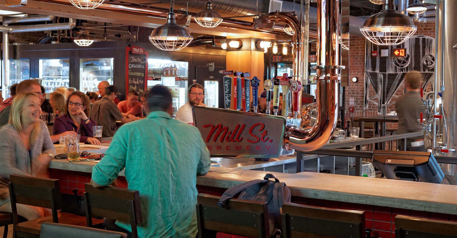 A group of people are sitting at a bar in a restaurant.