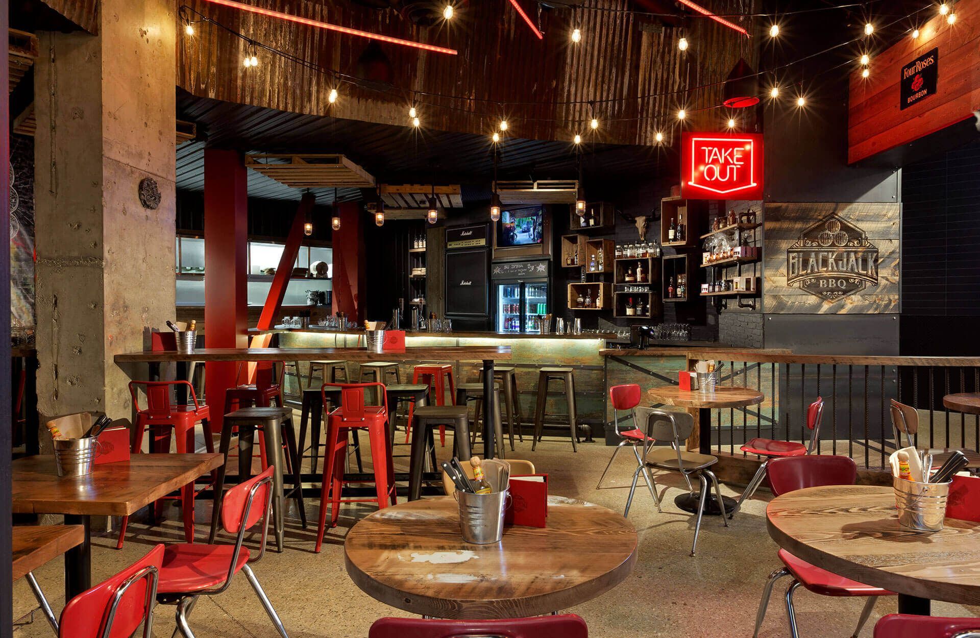 The inside of a restaurant with tables and chairs and a neon sign that says open