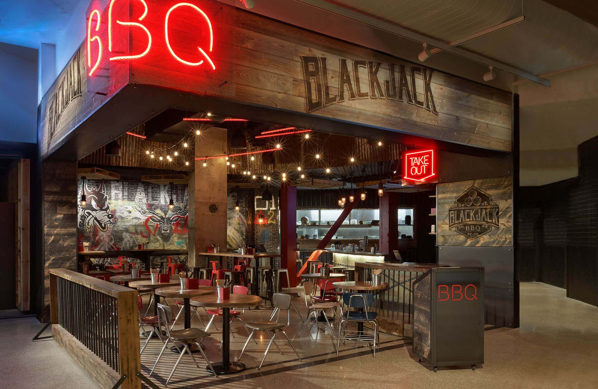 A restaurant with tables and chairs and a neon sign.