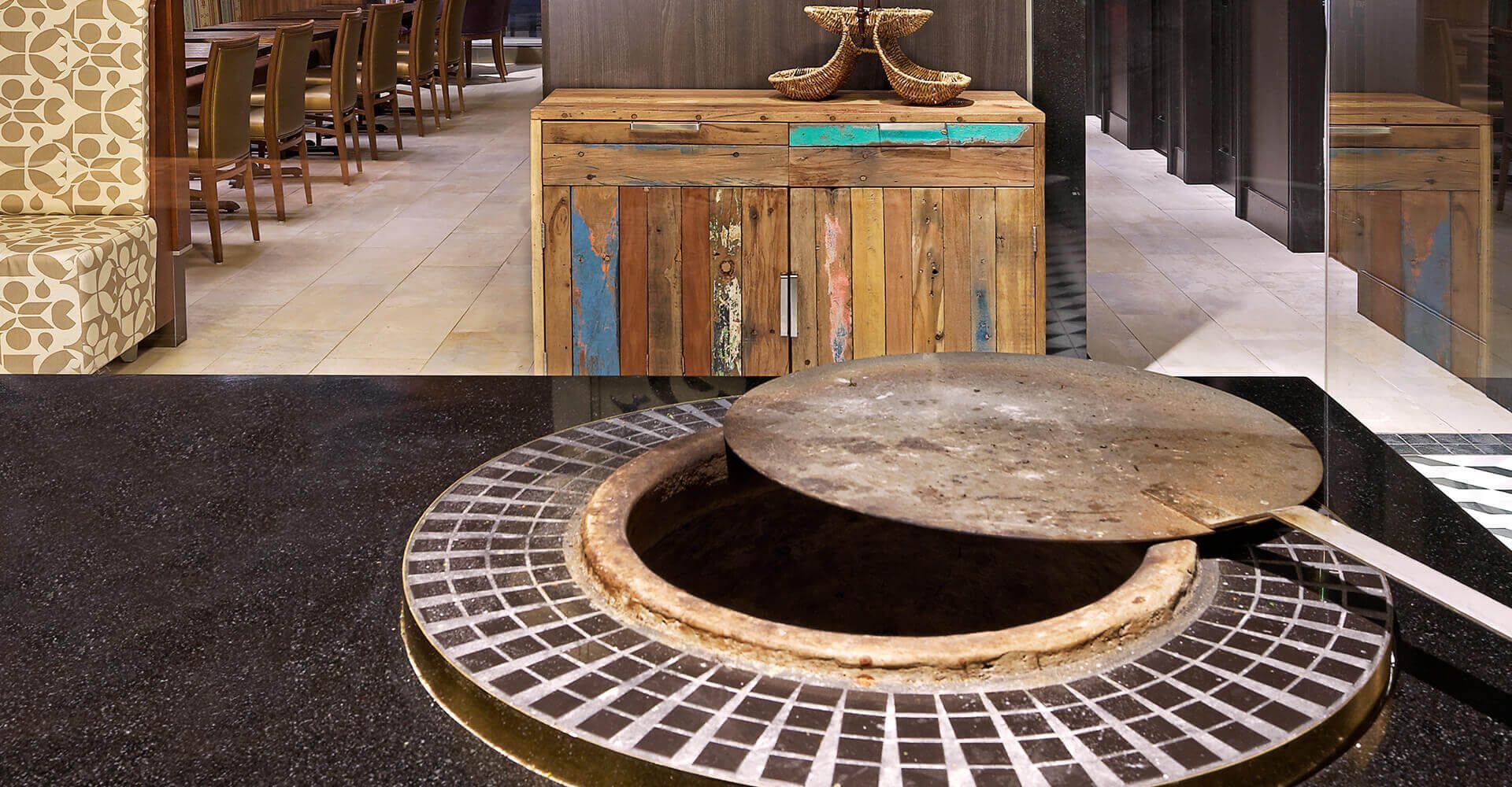 A circular table with a pizza pan on it in a restaurant.