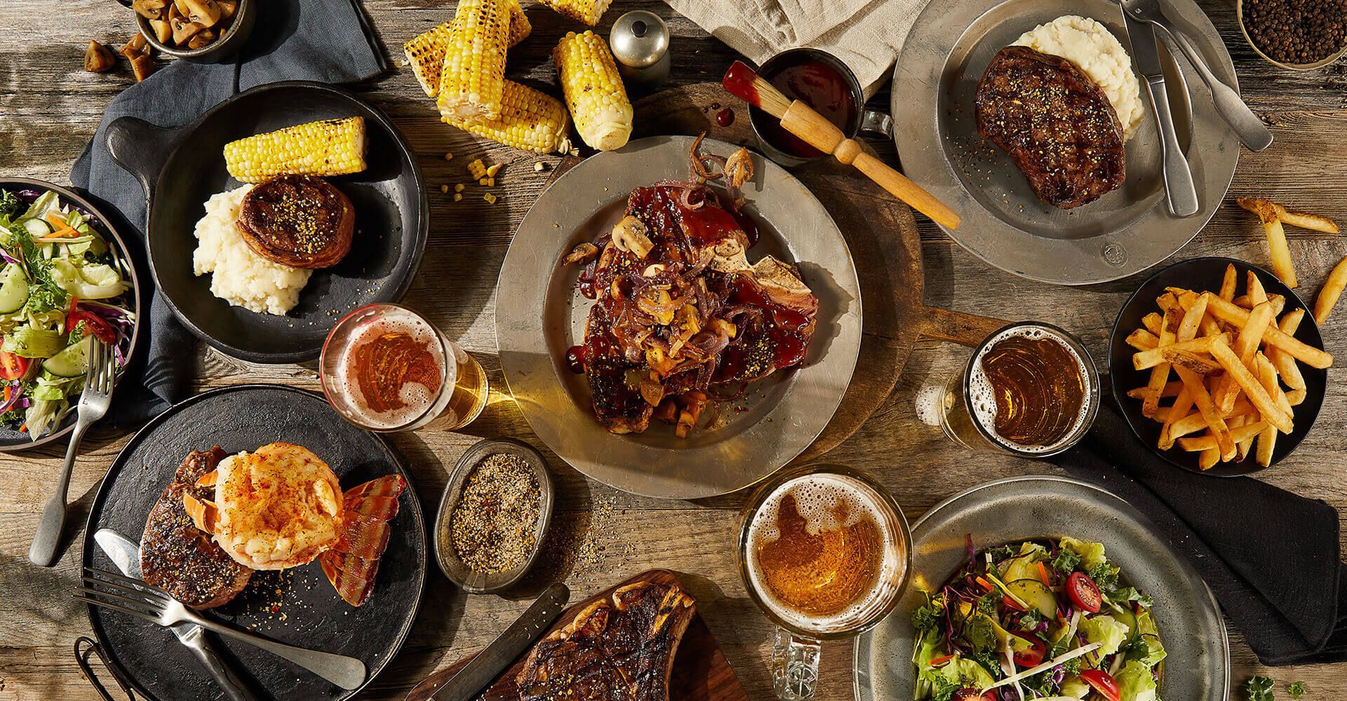 A wooden table topped with plates of food and drinks.