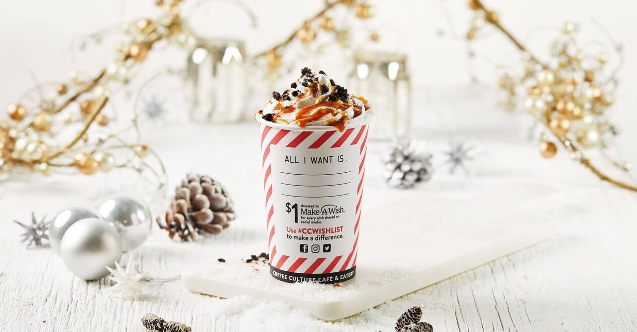 A cup of hot chocolate is sitting on a table with christmas decorations.