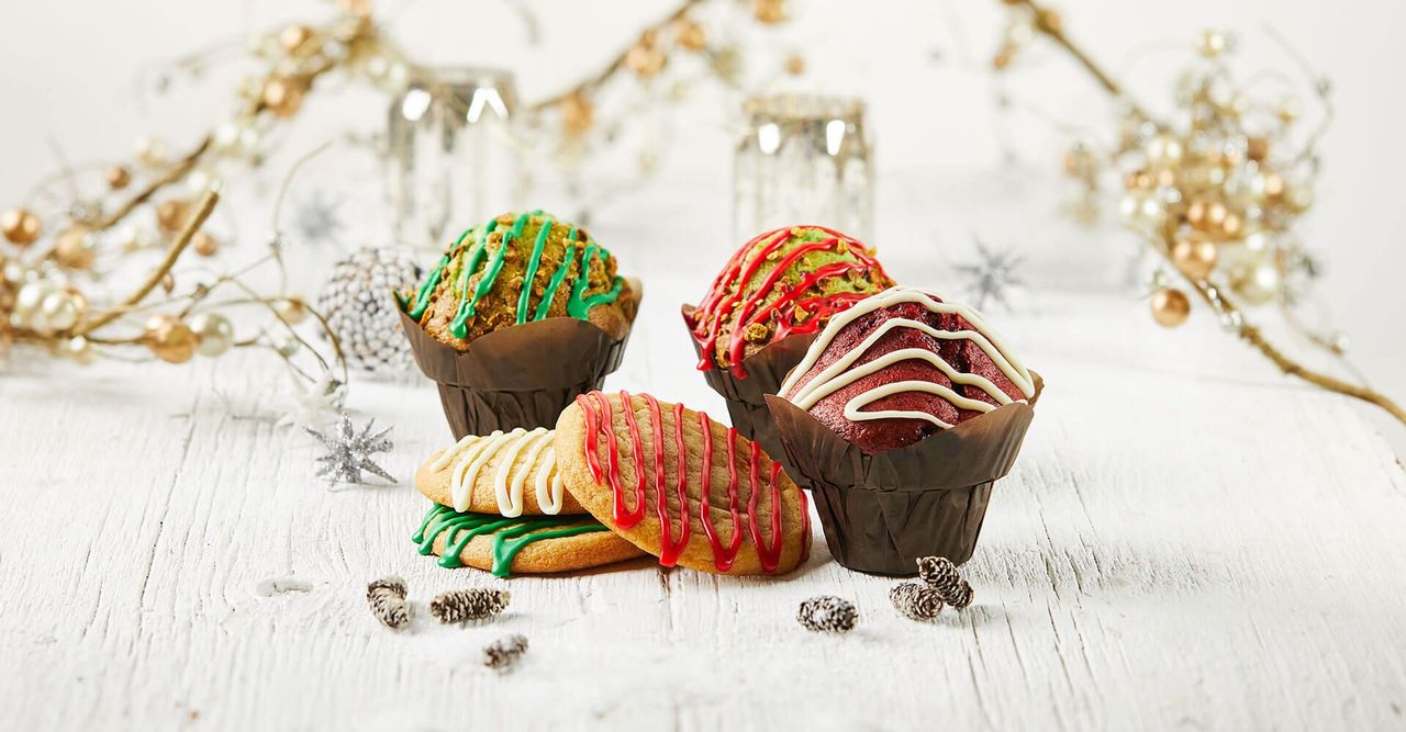 A table topped with cupcakes and cookies decorated for christmas.