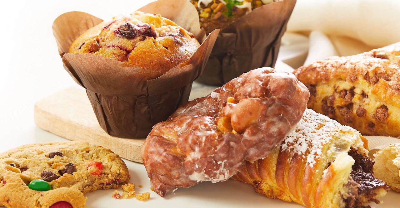 A variety of pastries and muffins are on a table.