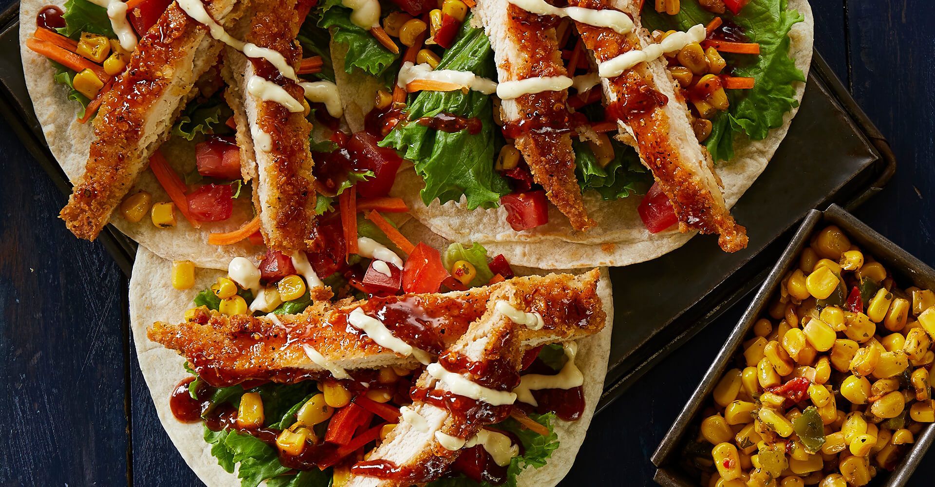A close up of three tacos with chicken and vegetables on a plate.