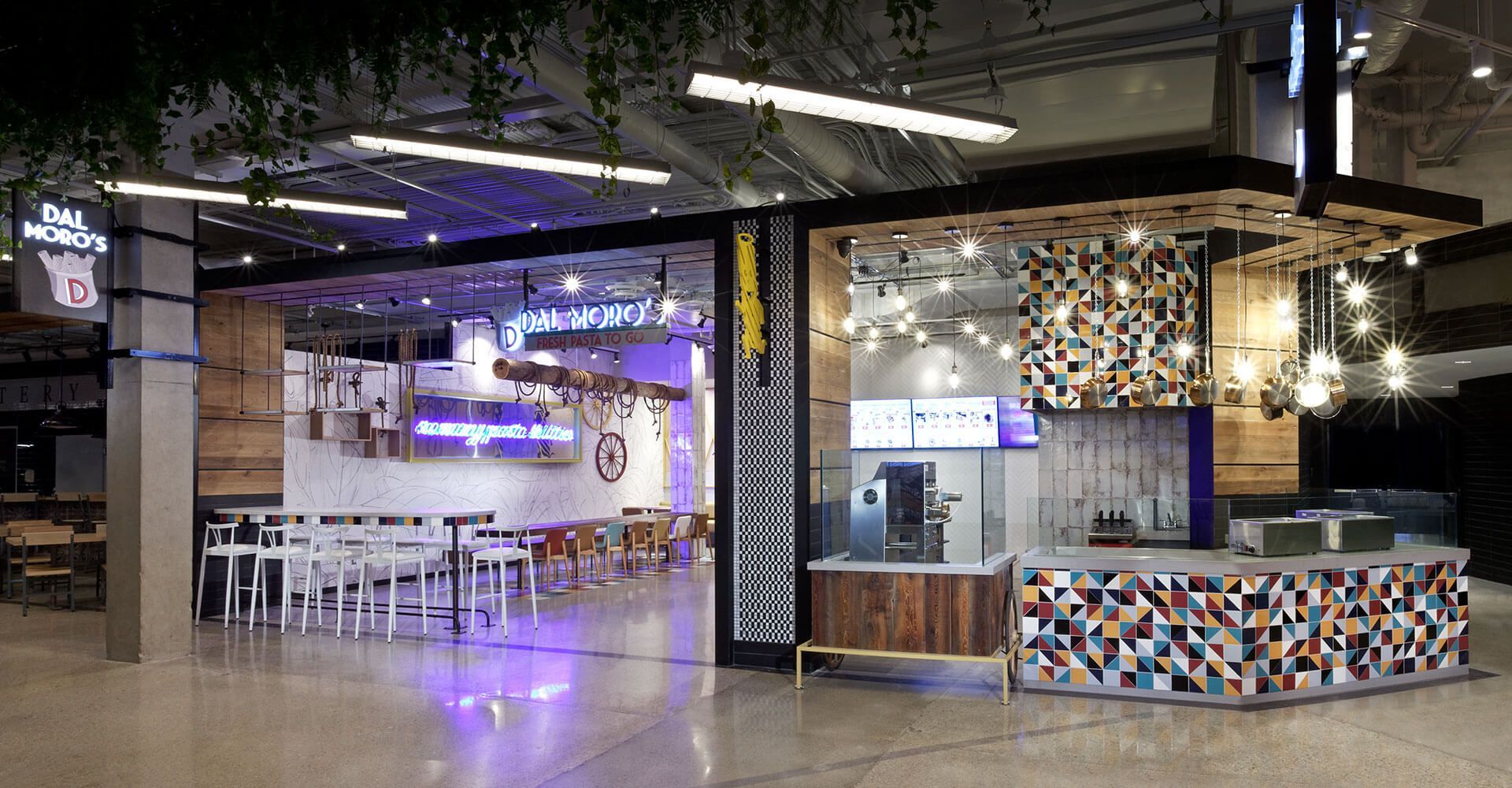 A restaurant with a purple light on the ceiling and tables and chairs.