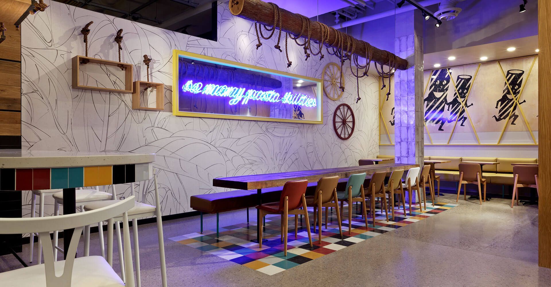 A restaurant with tables and chairs and a neon sign on the wall