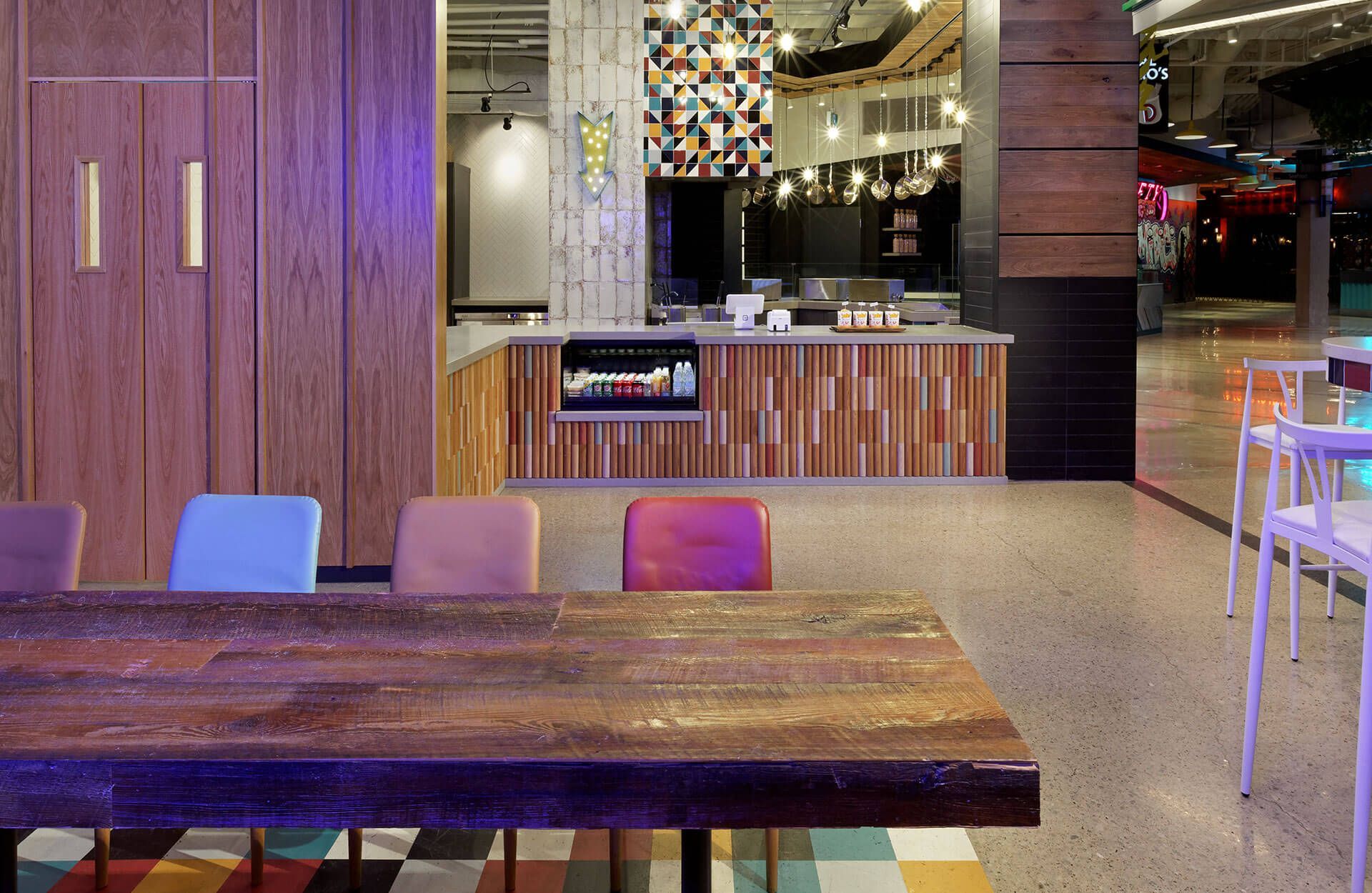 A wooden table and chairs in a restaurant with a counter in the background.