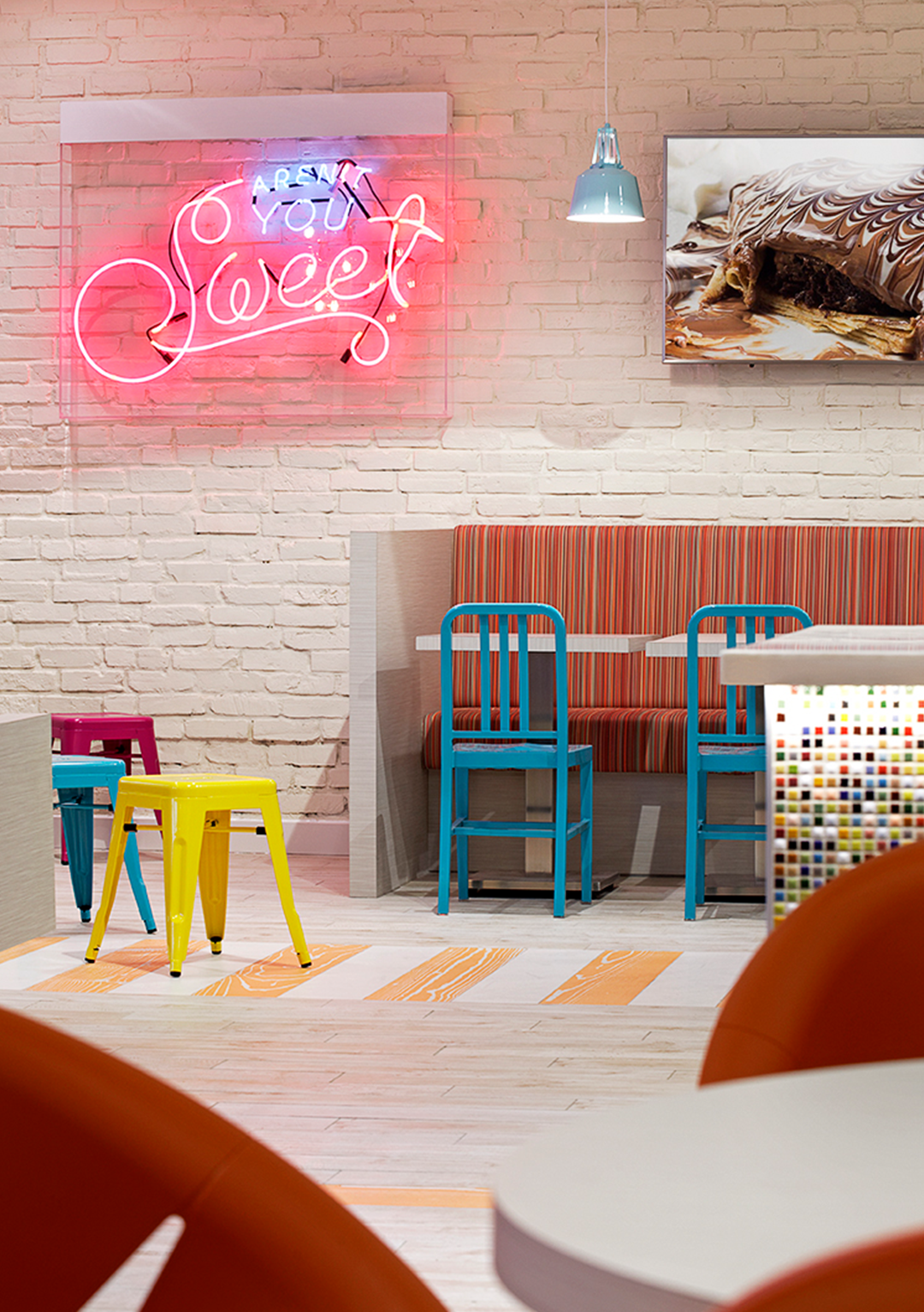A room with tables and chairs and a neon sign that says sweet