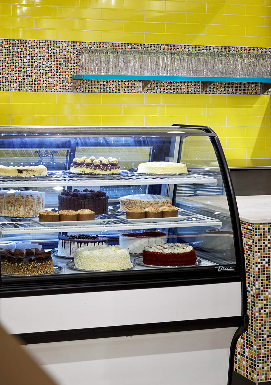 A display case filled with lots of cakes in a bakery.