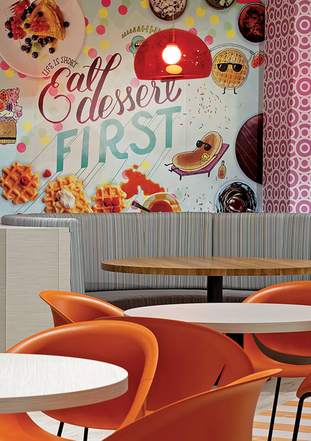 A restaurant with tables and chairs and a mural on the wall that says `` eat dessert first ''.