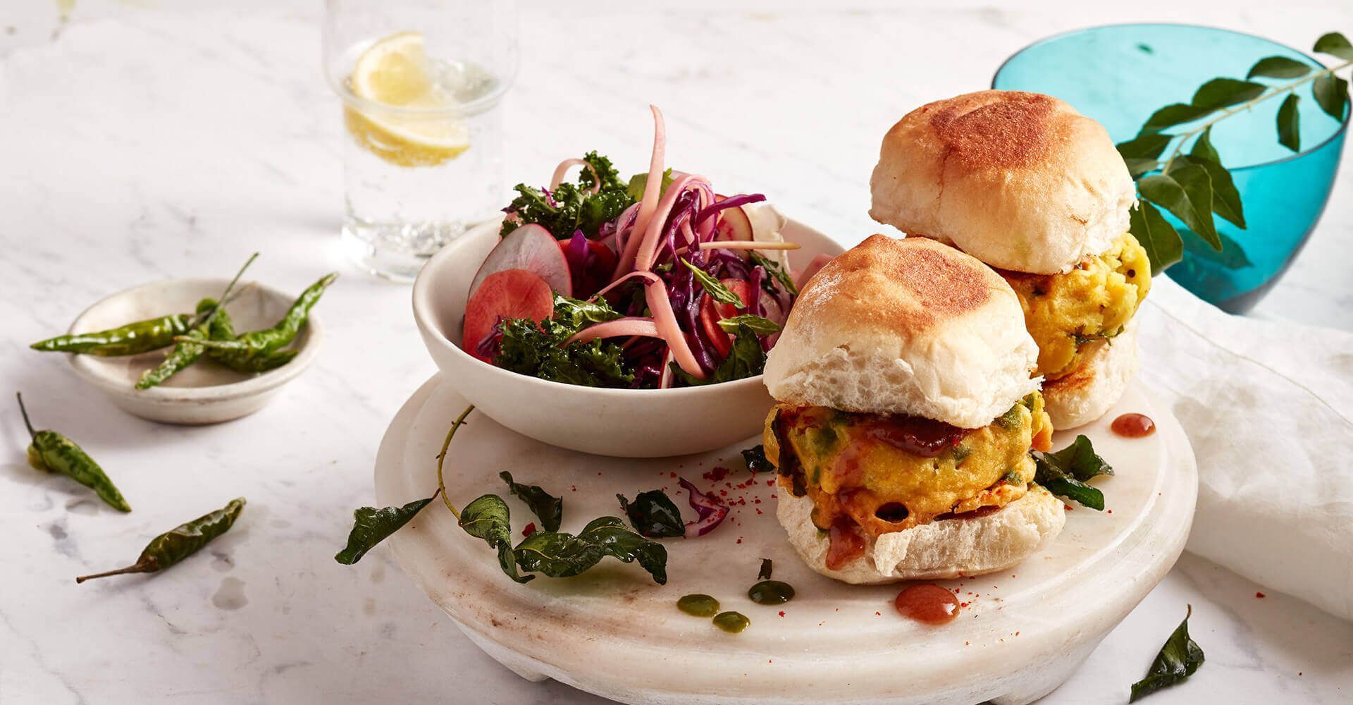 Two sandwiches are sitting on top of a white plate next to a bowl of salad.