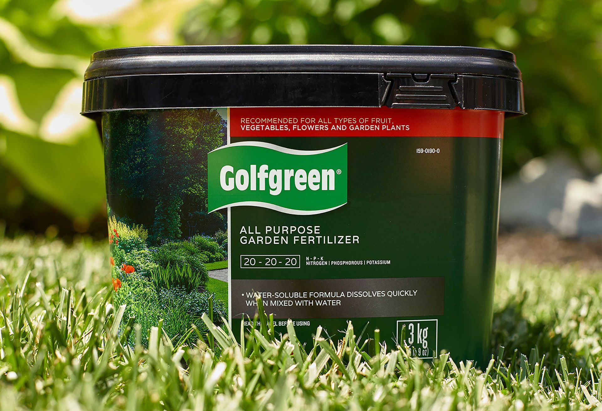 A bucket of golfgreen all purpose garden fertilizer is sitting in the grass