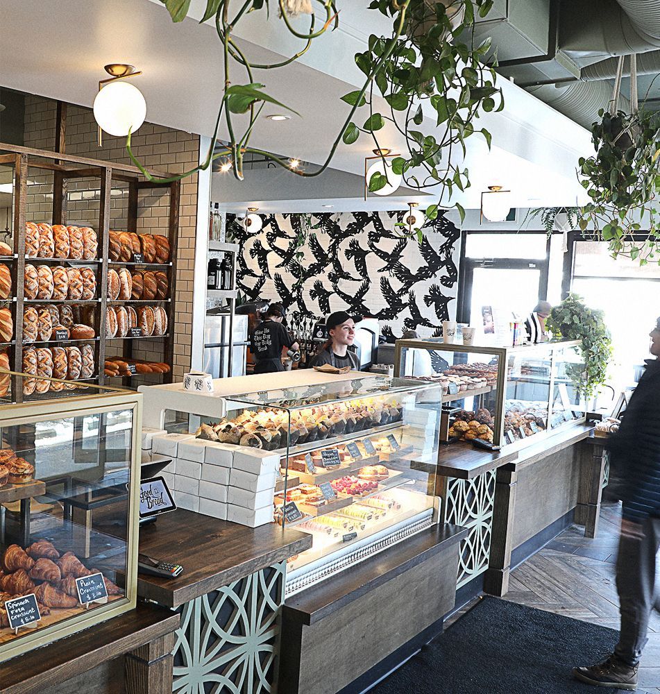 A woman is standing in front of a display case in a bakery.
