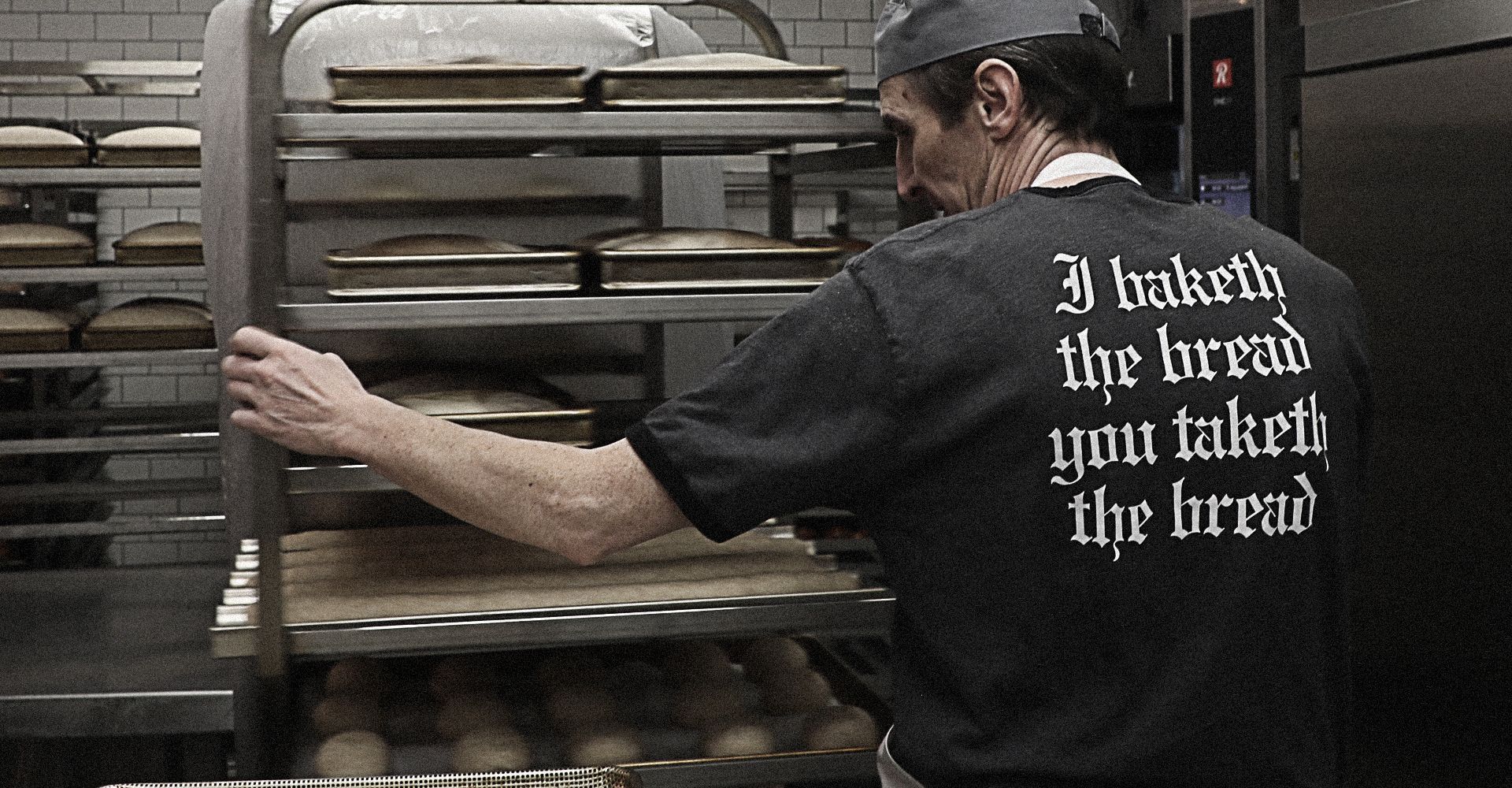 A man wearing a black shirt that says i take the bread you take the bread
