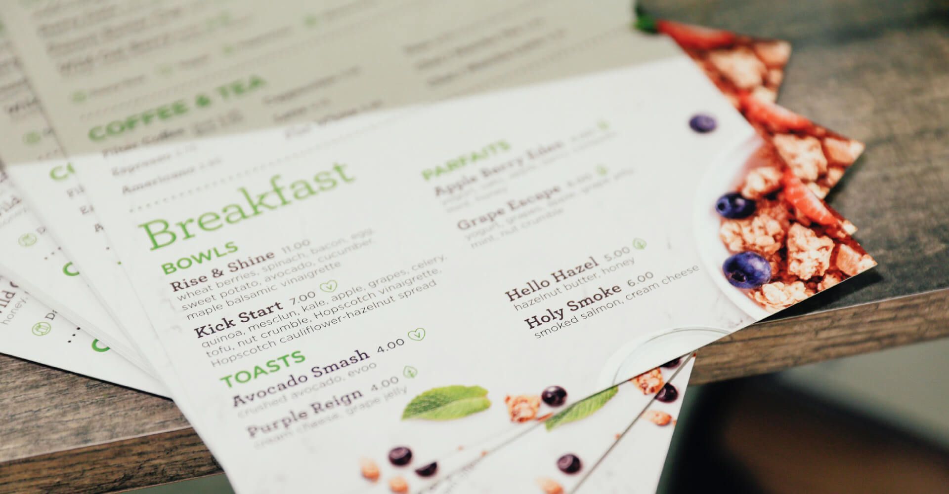 A stack of menus sitting on top of each other on a wooden table.