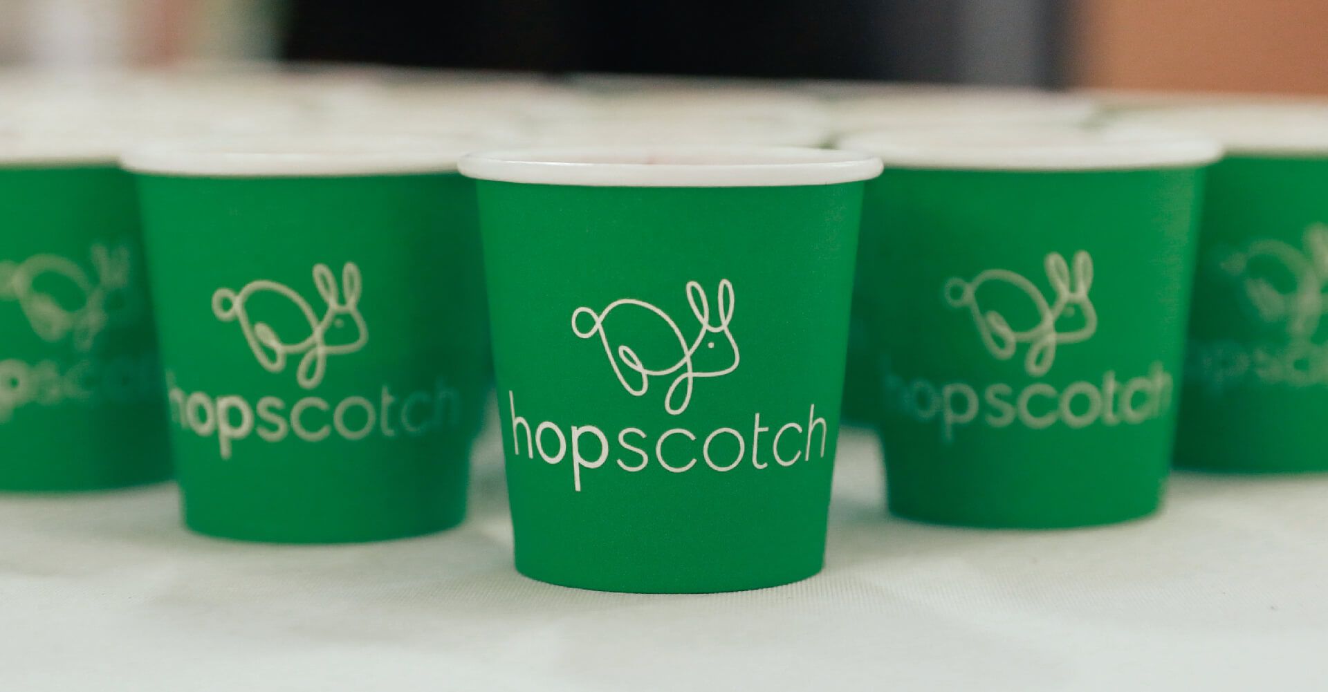 A row of green cups with the word hopscotch on them