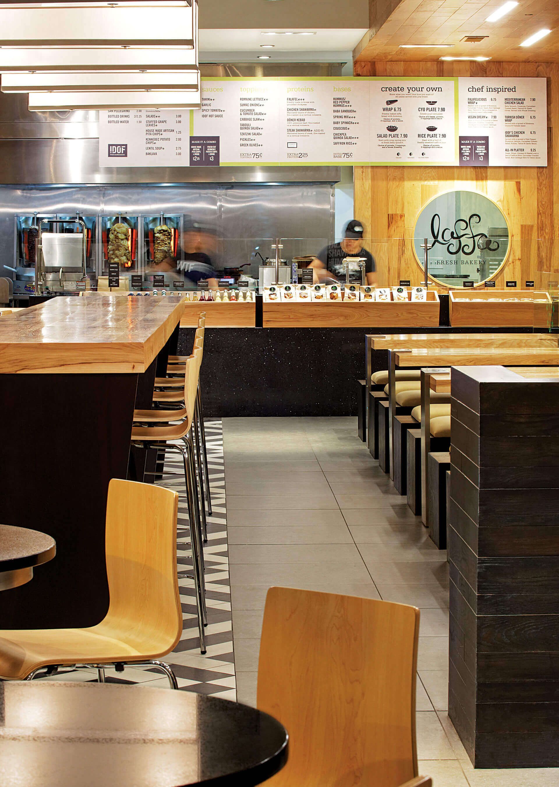 A restaurant with tables and chairs and a menu on the wall
