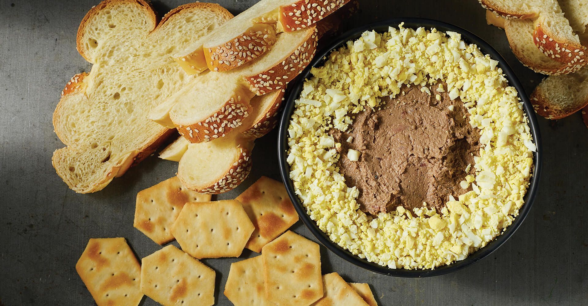 A bowl of food with crackers and bread on a table.