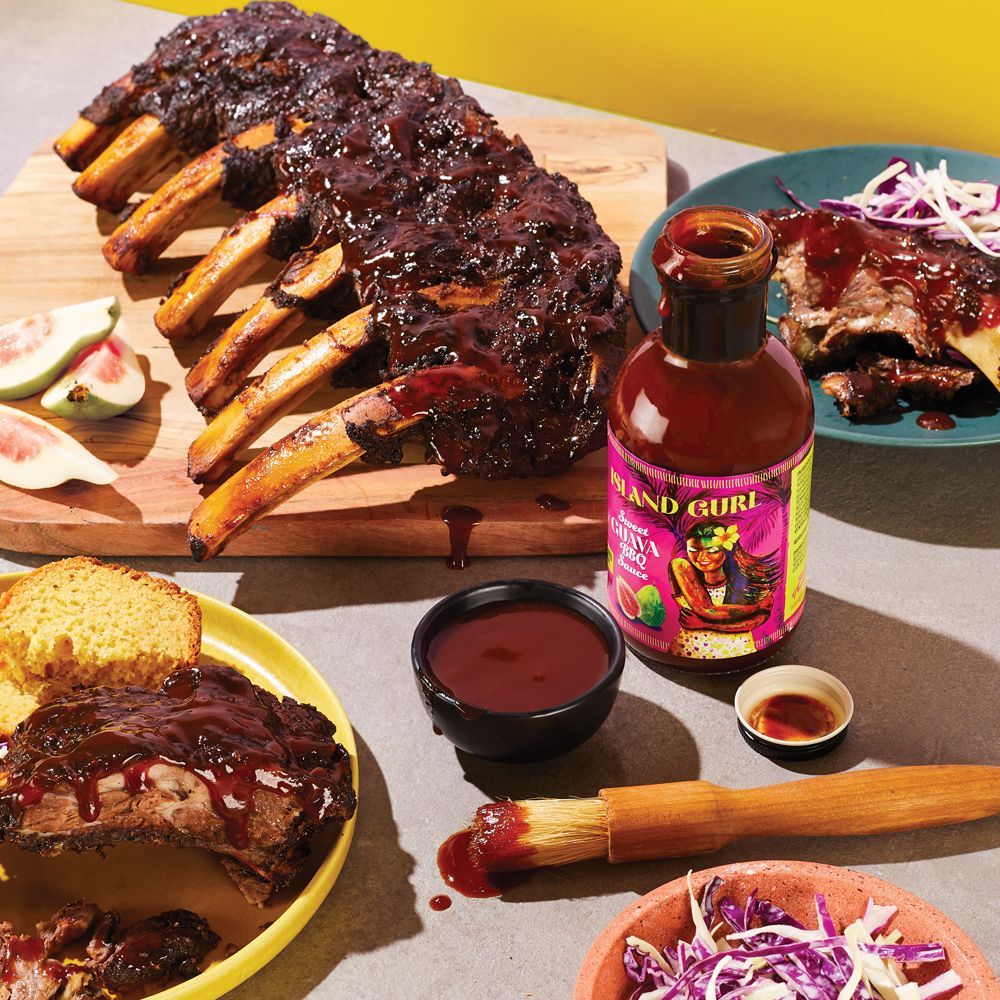 A table topped with plates of food and a bottle of barbecue sauce.