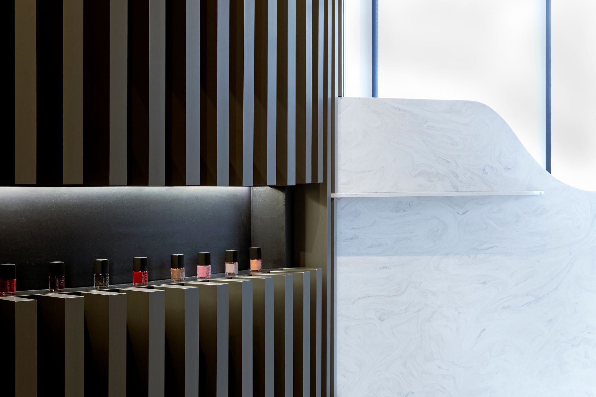 A row of nail polish bottles on a shelf in a store.