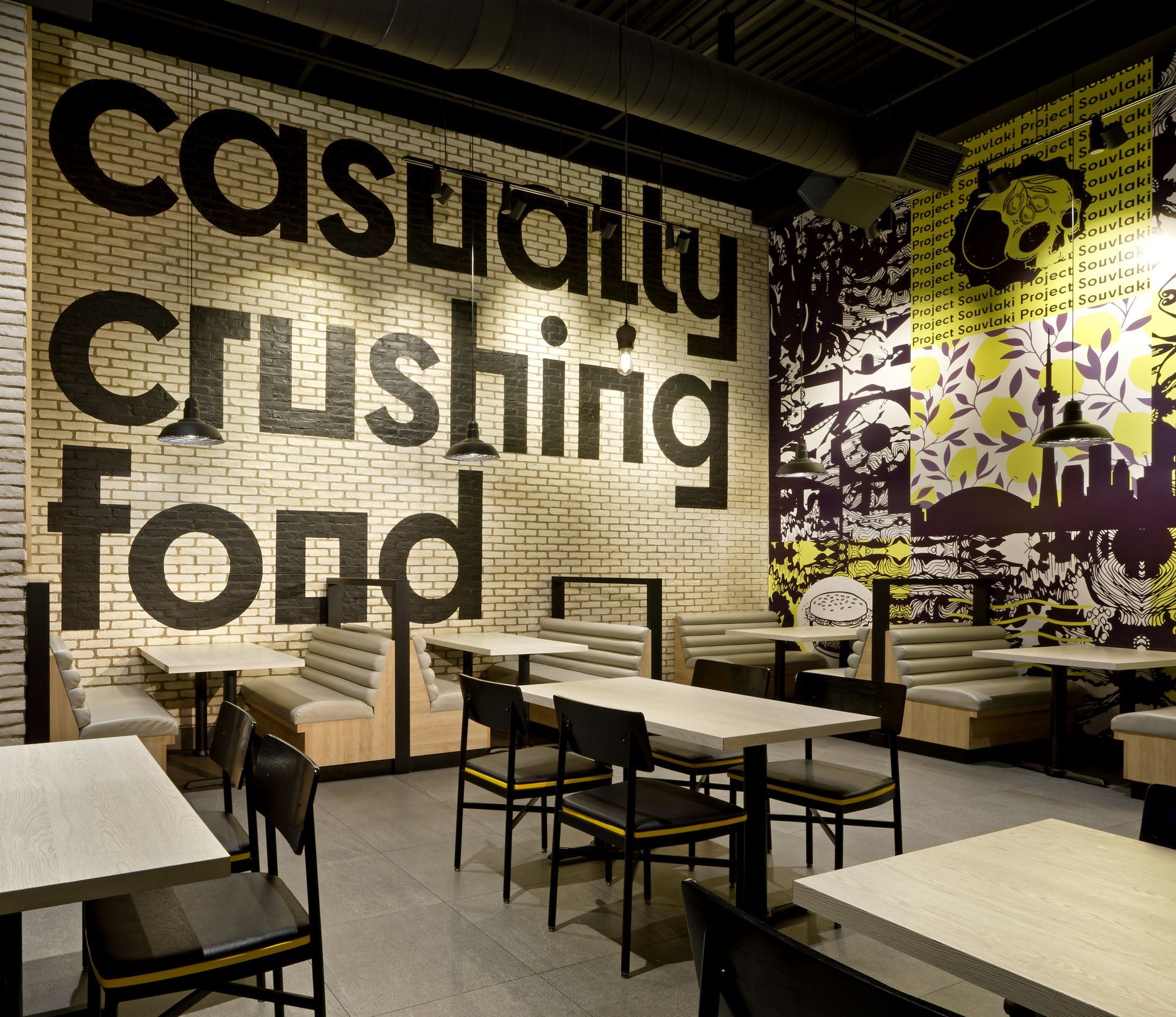 A restaurant with tables and chairs and a wall that says casually crushing fond