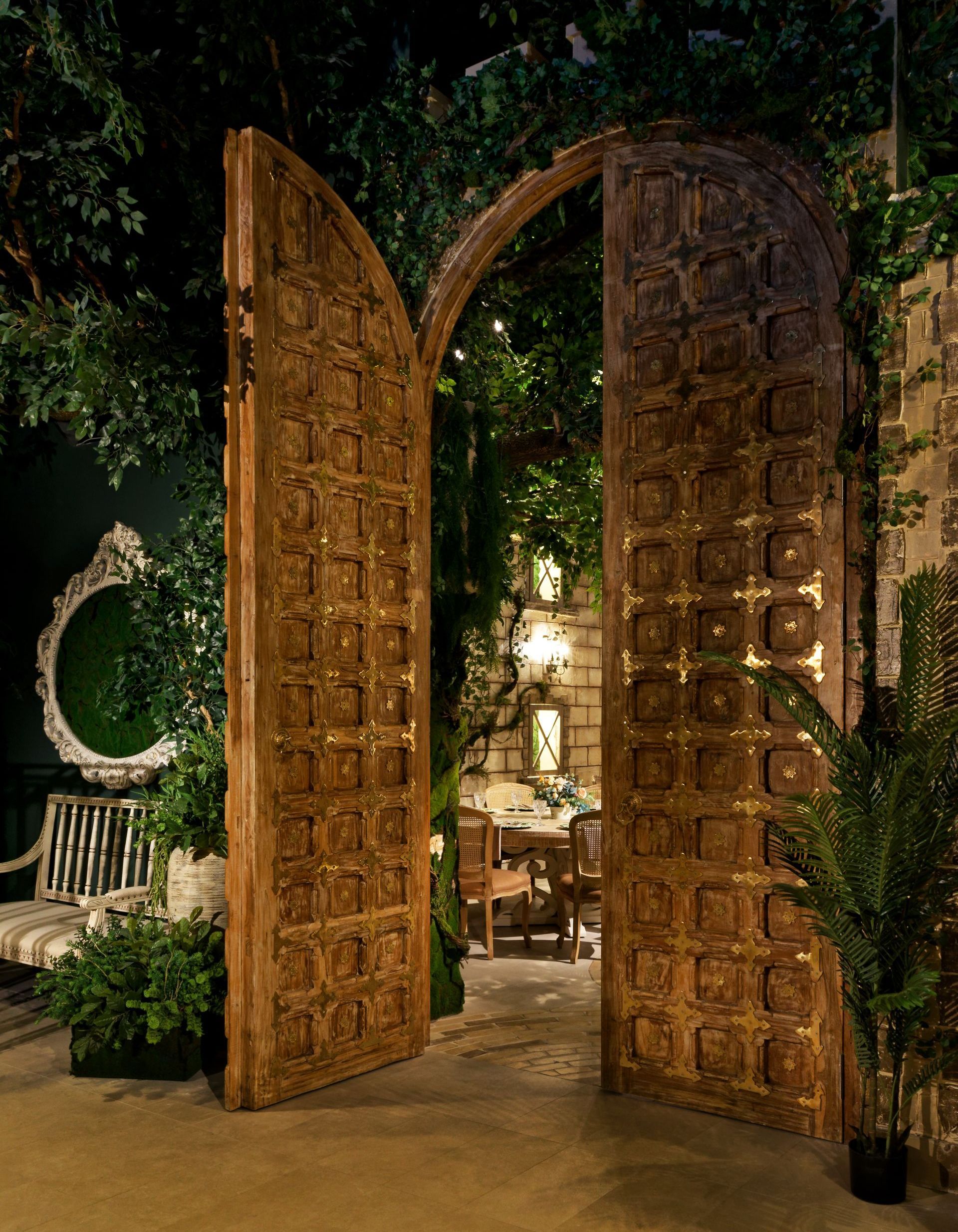 A large wooden door is open to a lush green room.