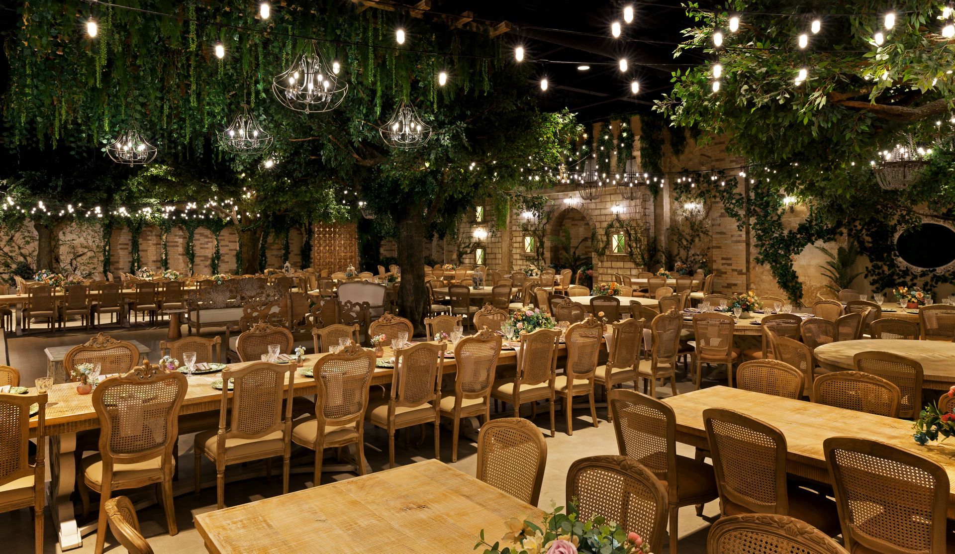 A large dining room with tables and chairs and trees hanging from the ceiling.