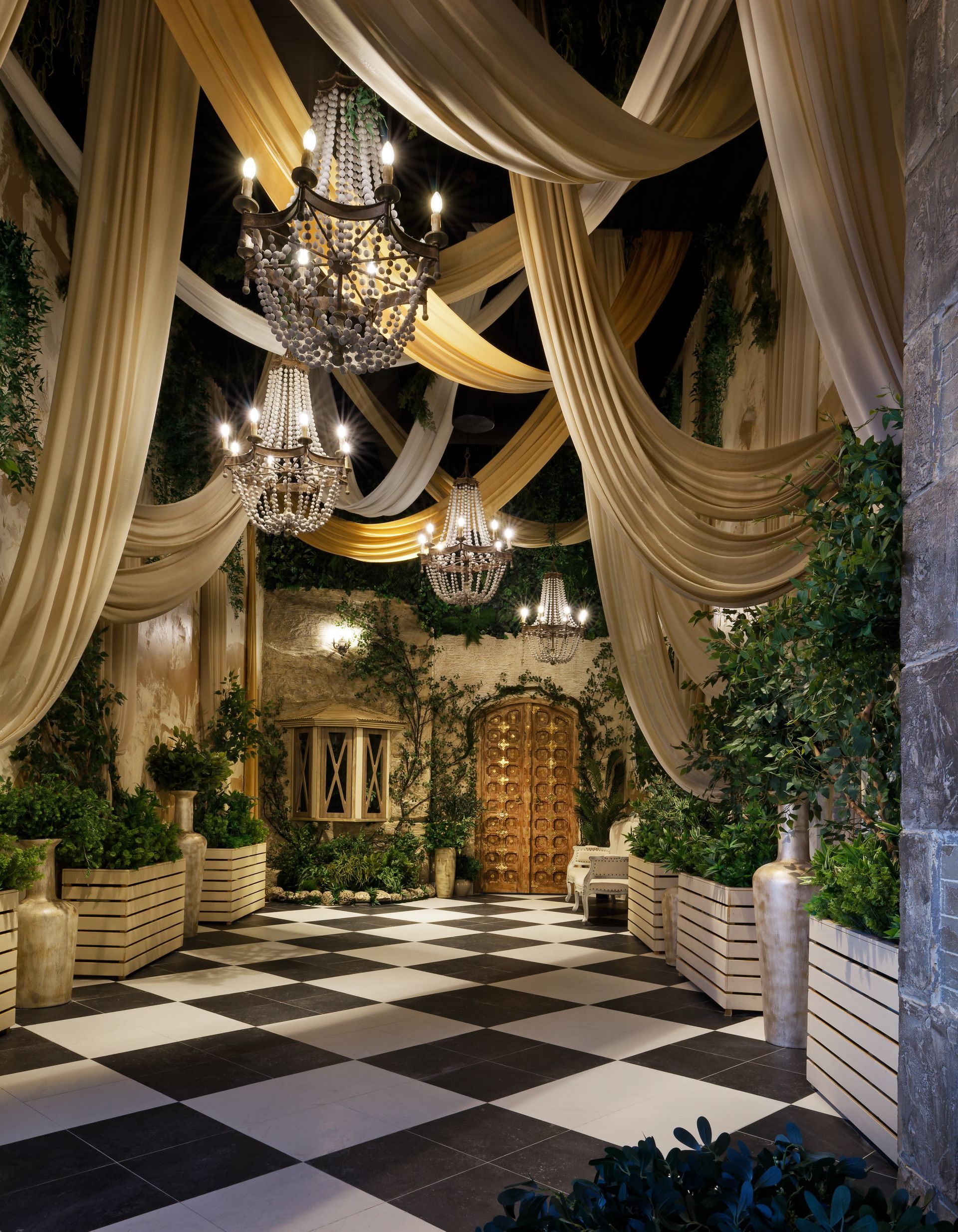 A room with a checkered floor and chandeliers hanging from the ceiling