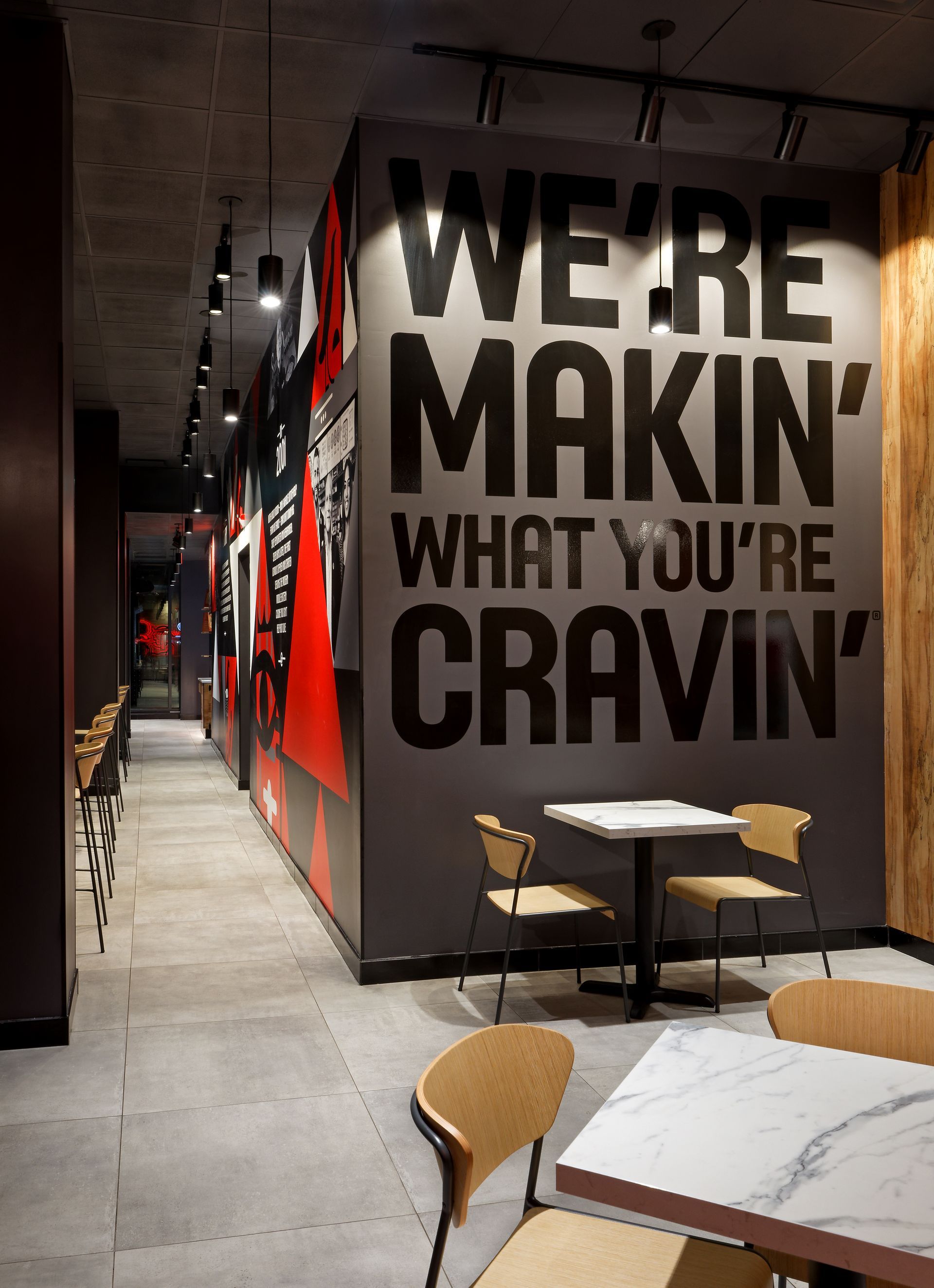 A restaurant with tables and chairs and a wall that says we 're makin ' what you 're cravin '