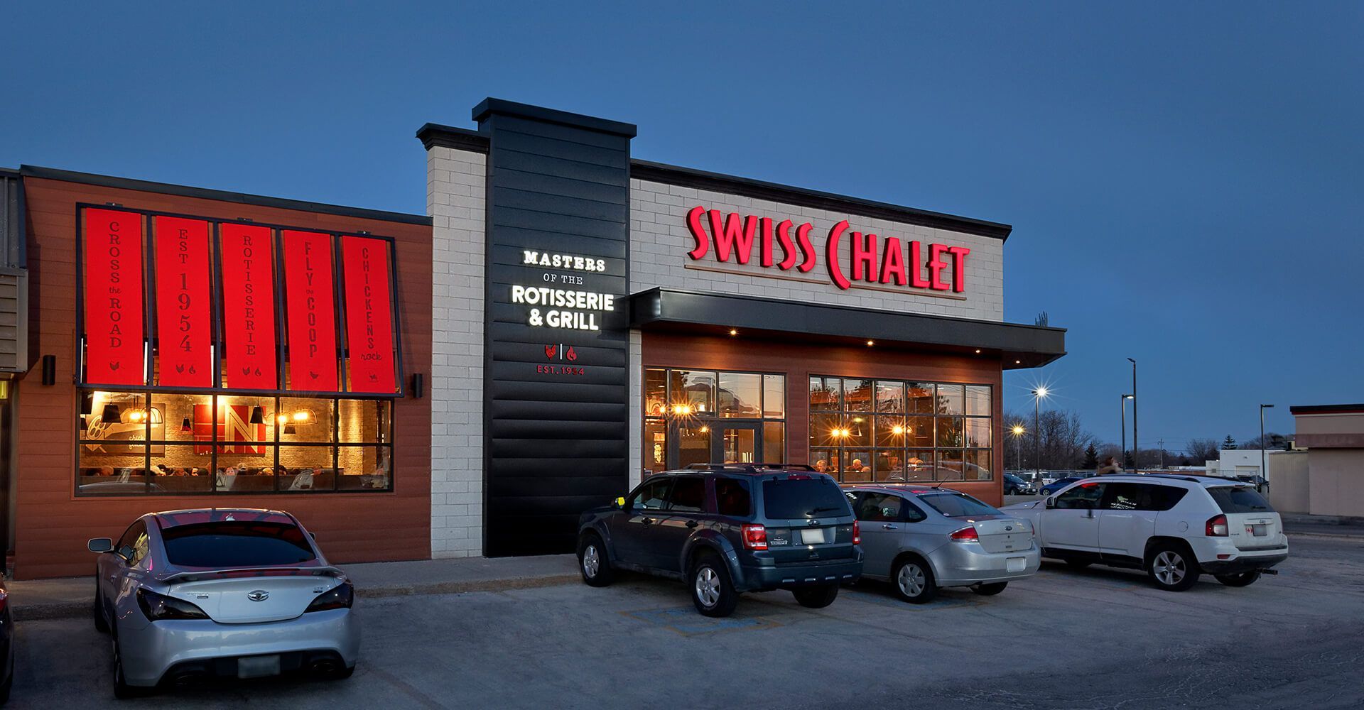 A row of cars are parked in front of a swiss quality restaurant.