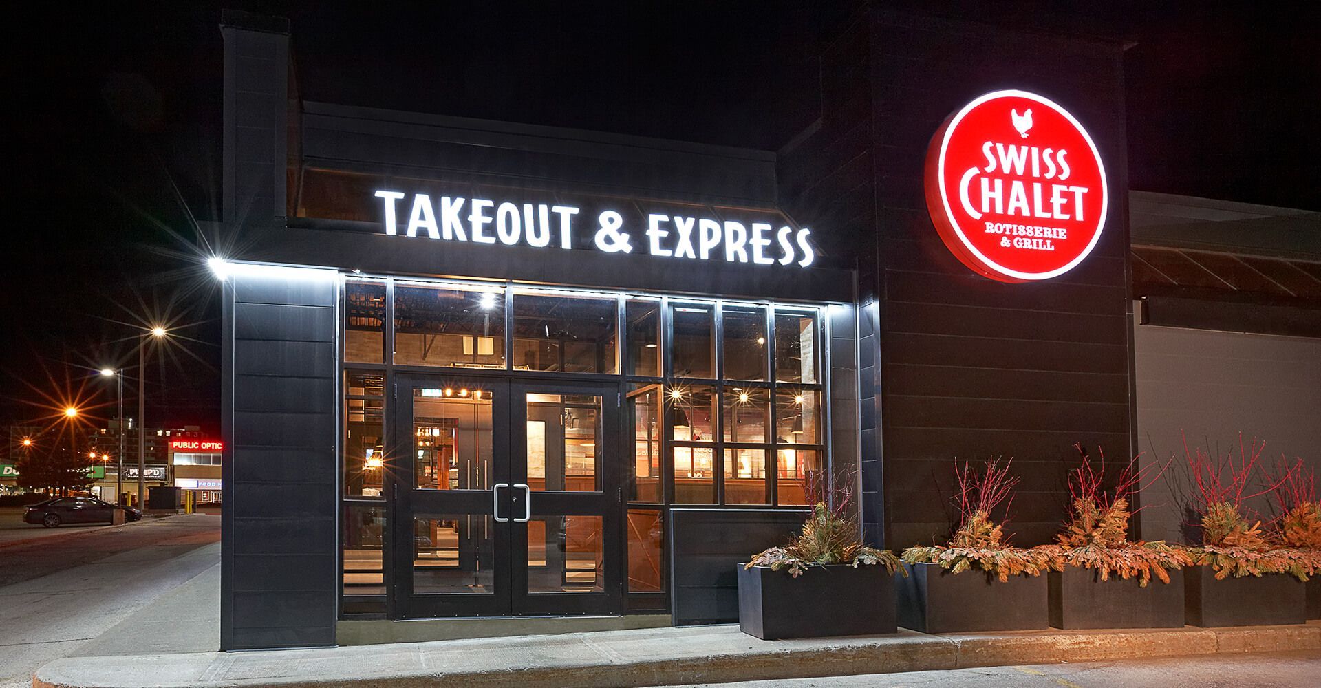 A swiss chalet takeout and express restaurant is lit up at night