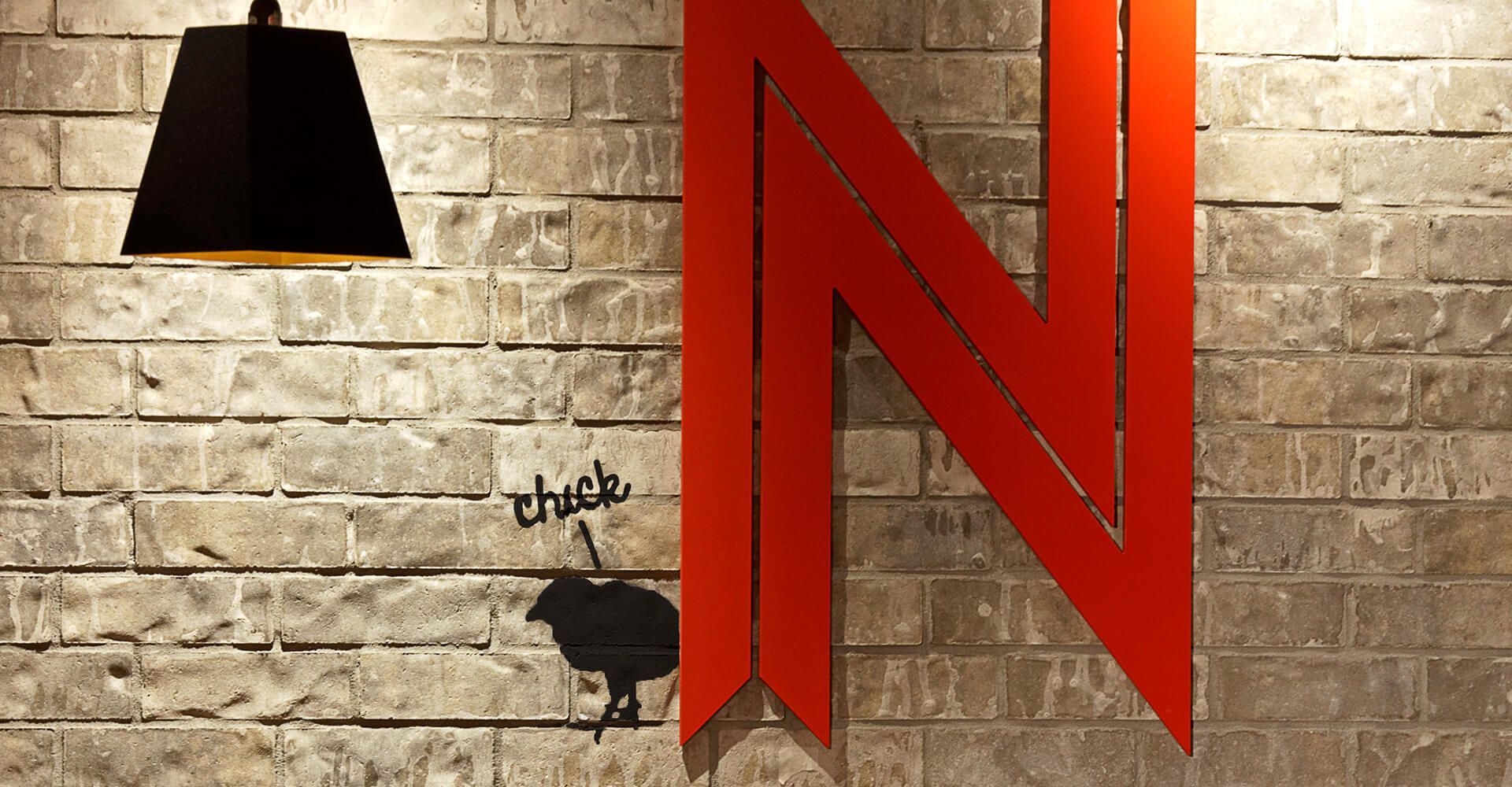 A red letter n is on a brick wall next to a lamp.
