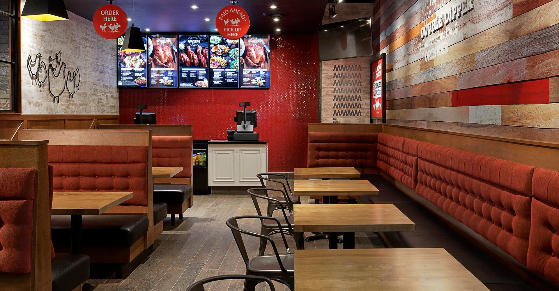 A restaurant with tables and chairs and a large screen on the wall.