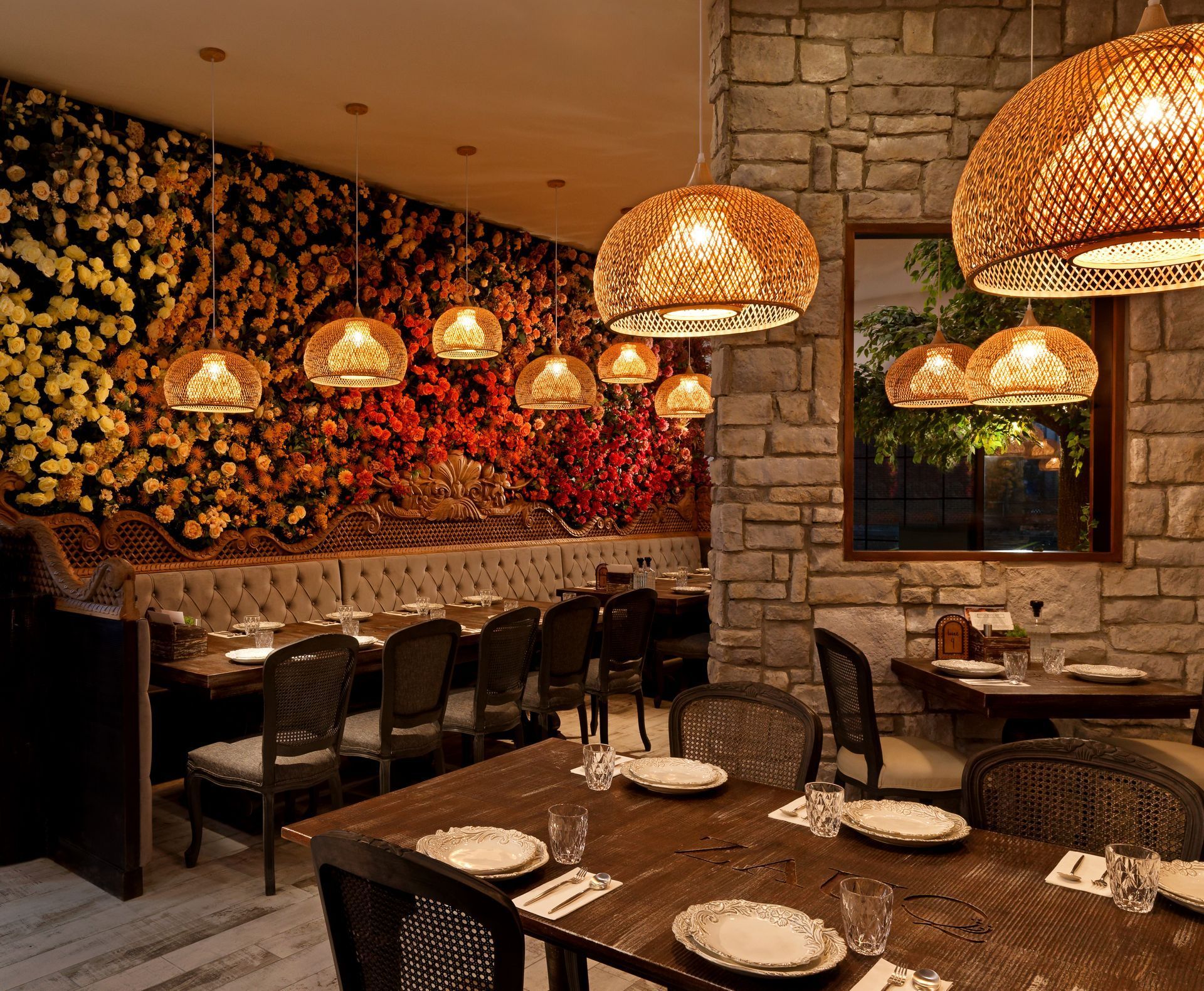 A restaurant with tables and chairs and wicker lamps hanging from the ceiling