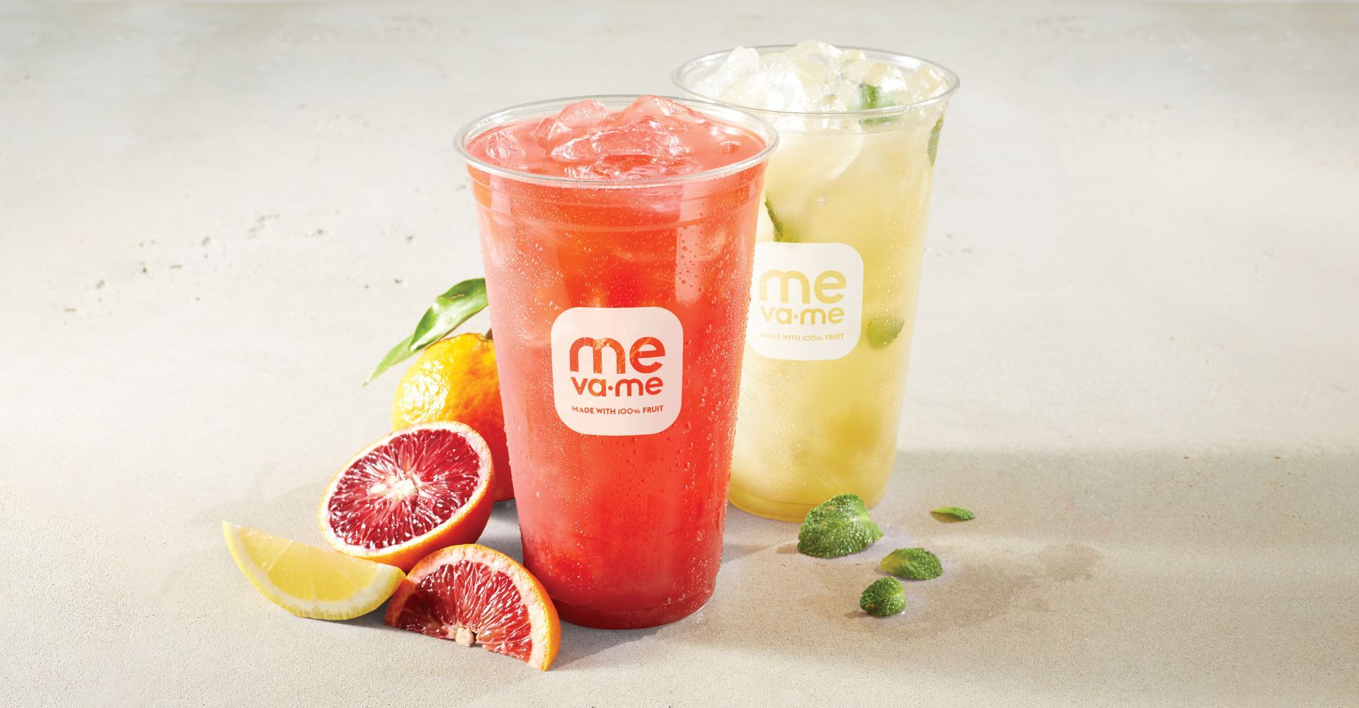 Two cups of drinks are sitting on a table next to grapefruit slices.