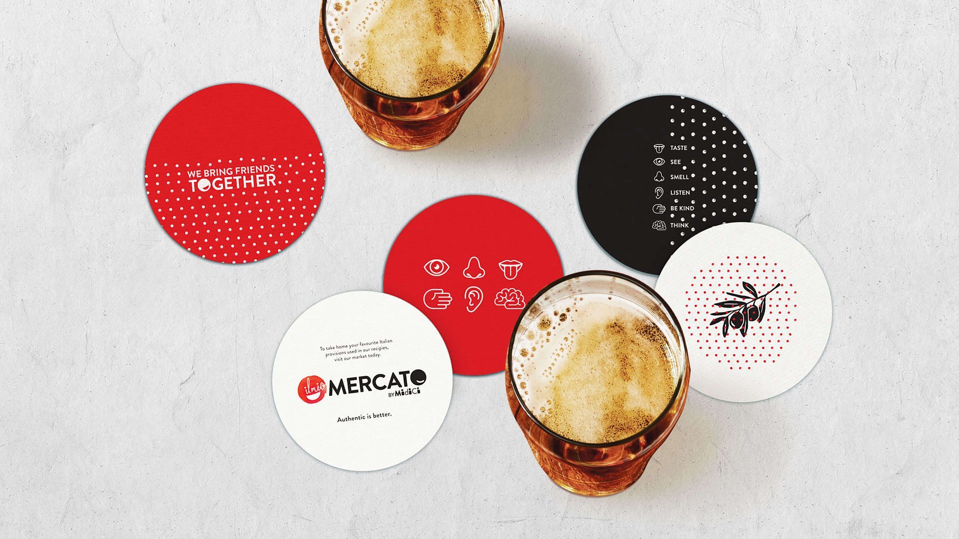 A couple of glasses of beer sitting on top of a table surrounded by coasters.