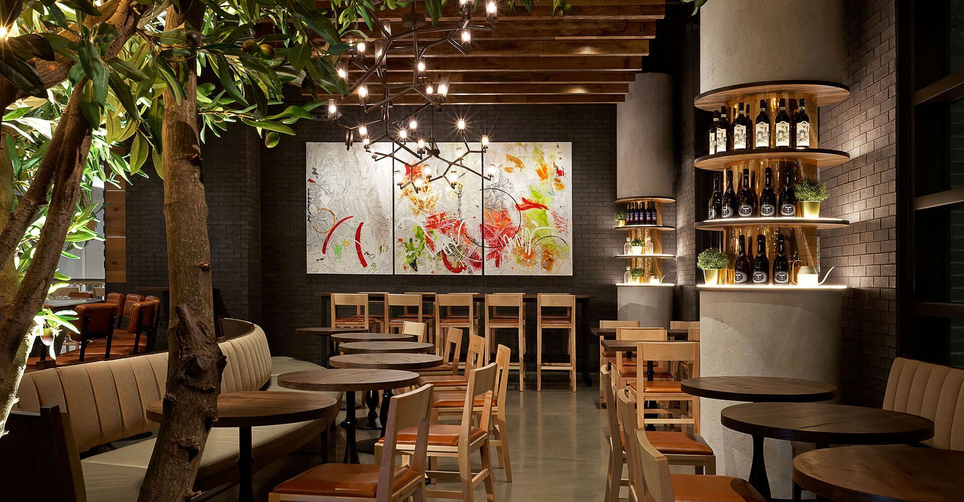 A restaurant with tables and chairs and a tree in the middle of the room.