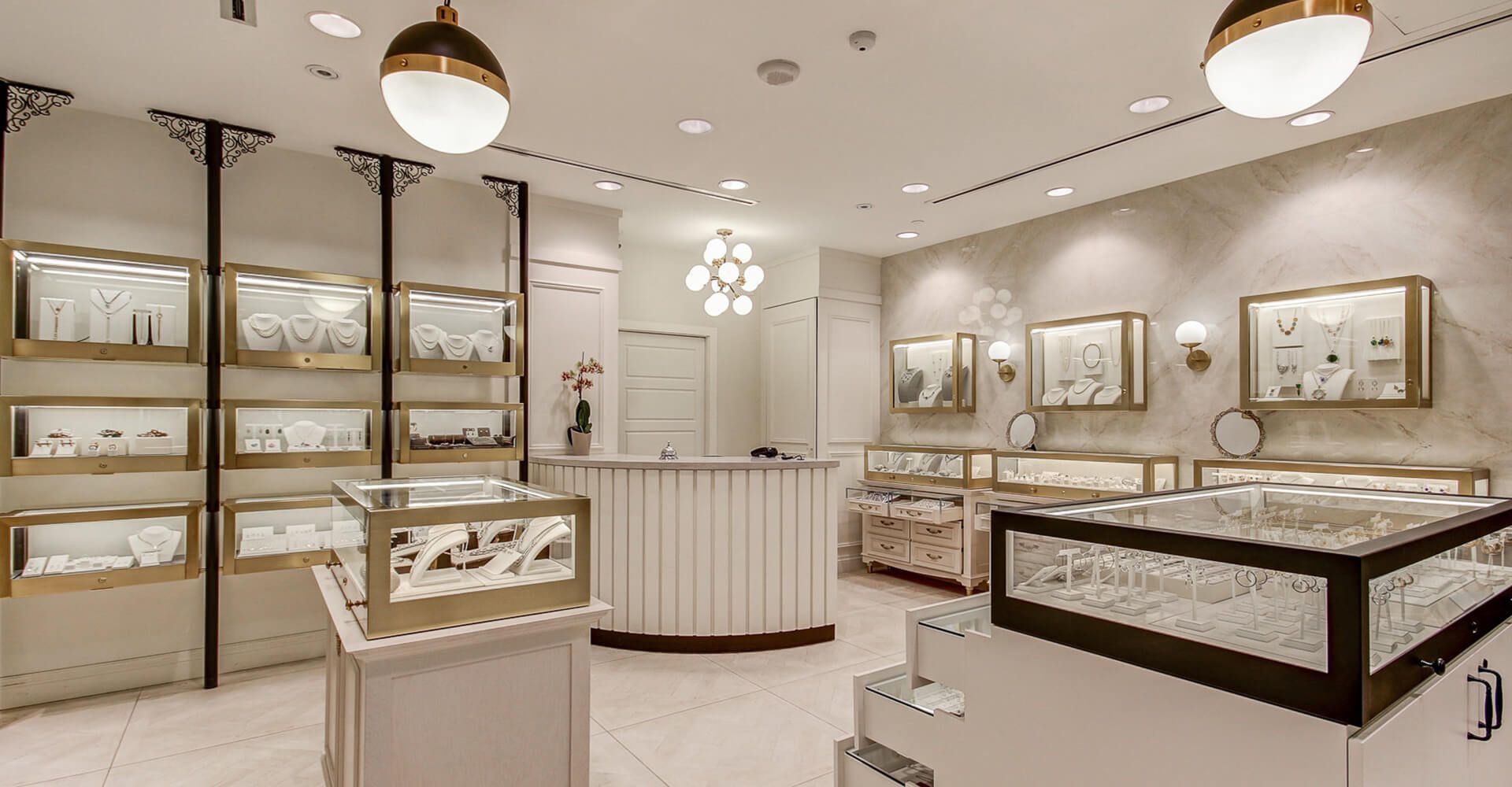 A jewelry store with a reception desk and display cases filled with jewelry.