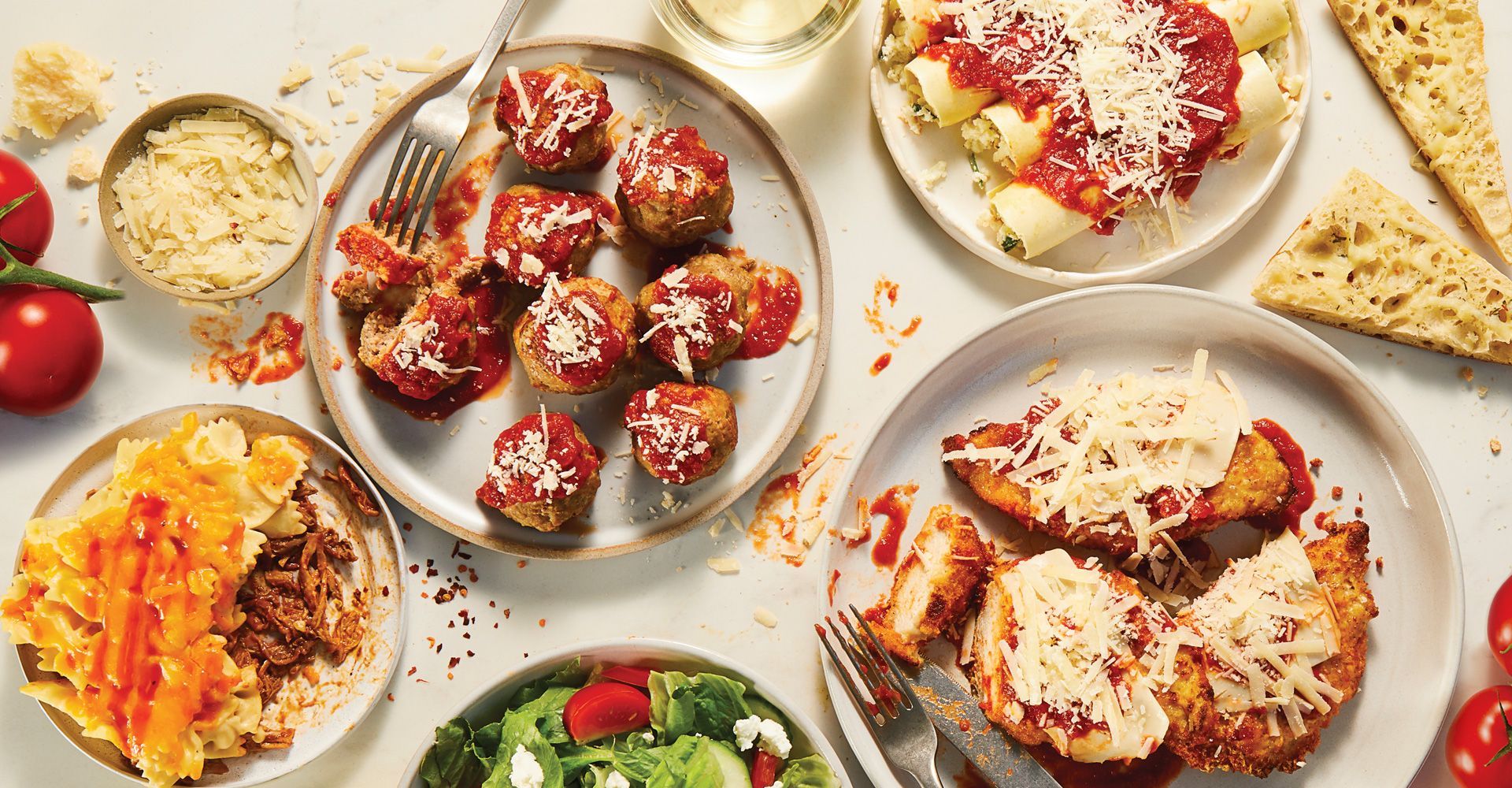 A table topped with plates of food and a glass of wine.