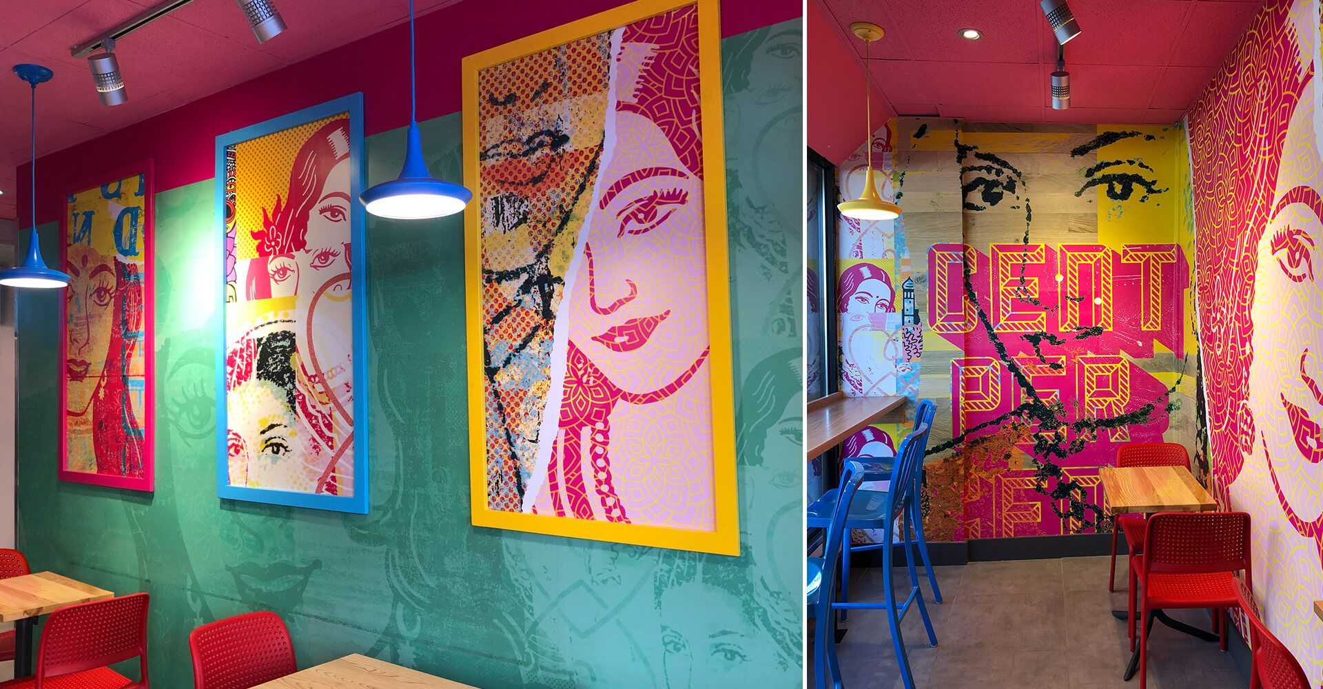 A restaurant with a lot of colorful paintings on the walls and tables and chairs.